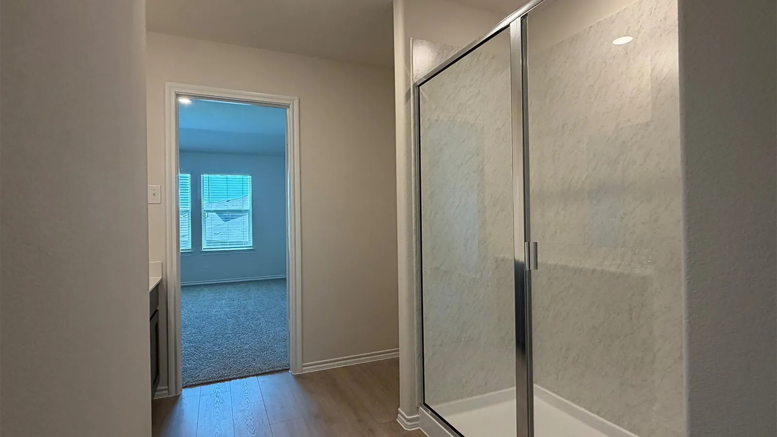 Shower enclosure with a clear glass door, chrome frame, and textured wall surround