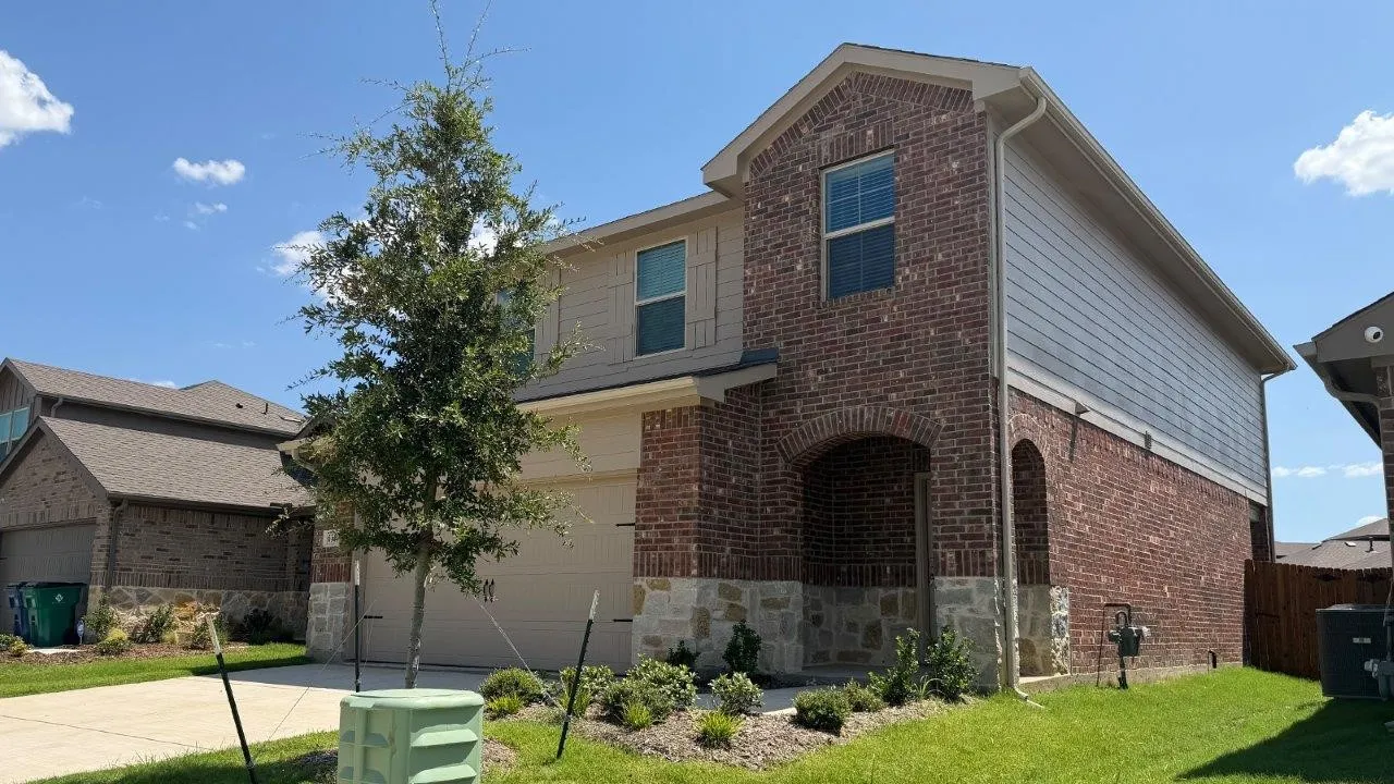 Two-story residence featuring a brick and stone facade, arched entry, and an attached garage