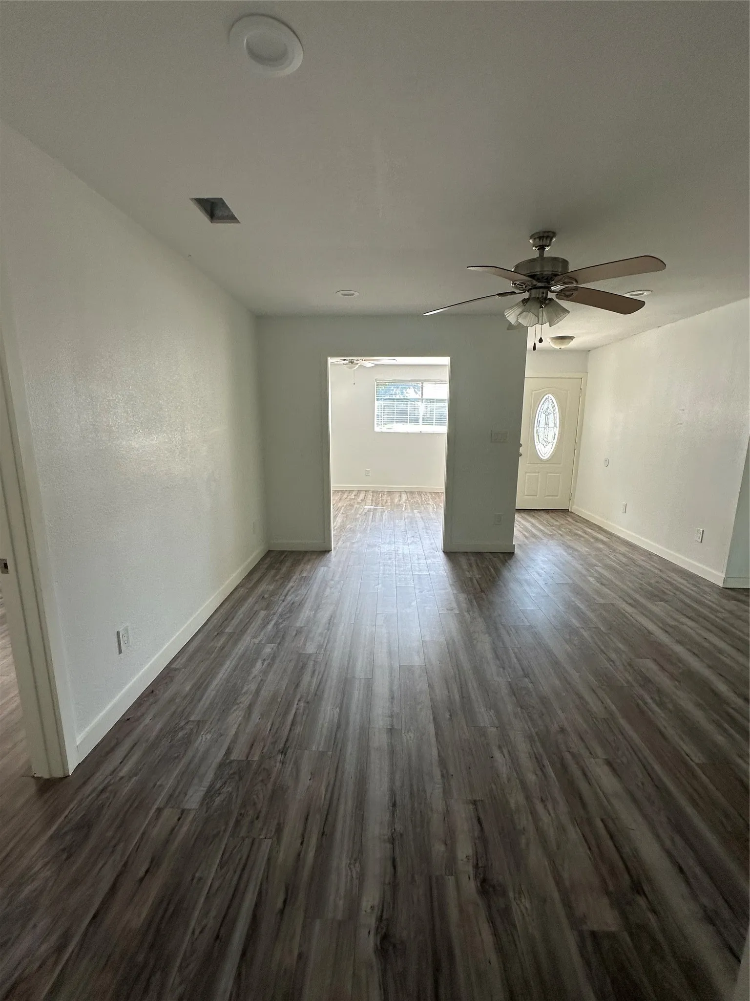 View of living room, study/office room, and entryway from the hallway.