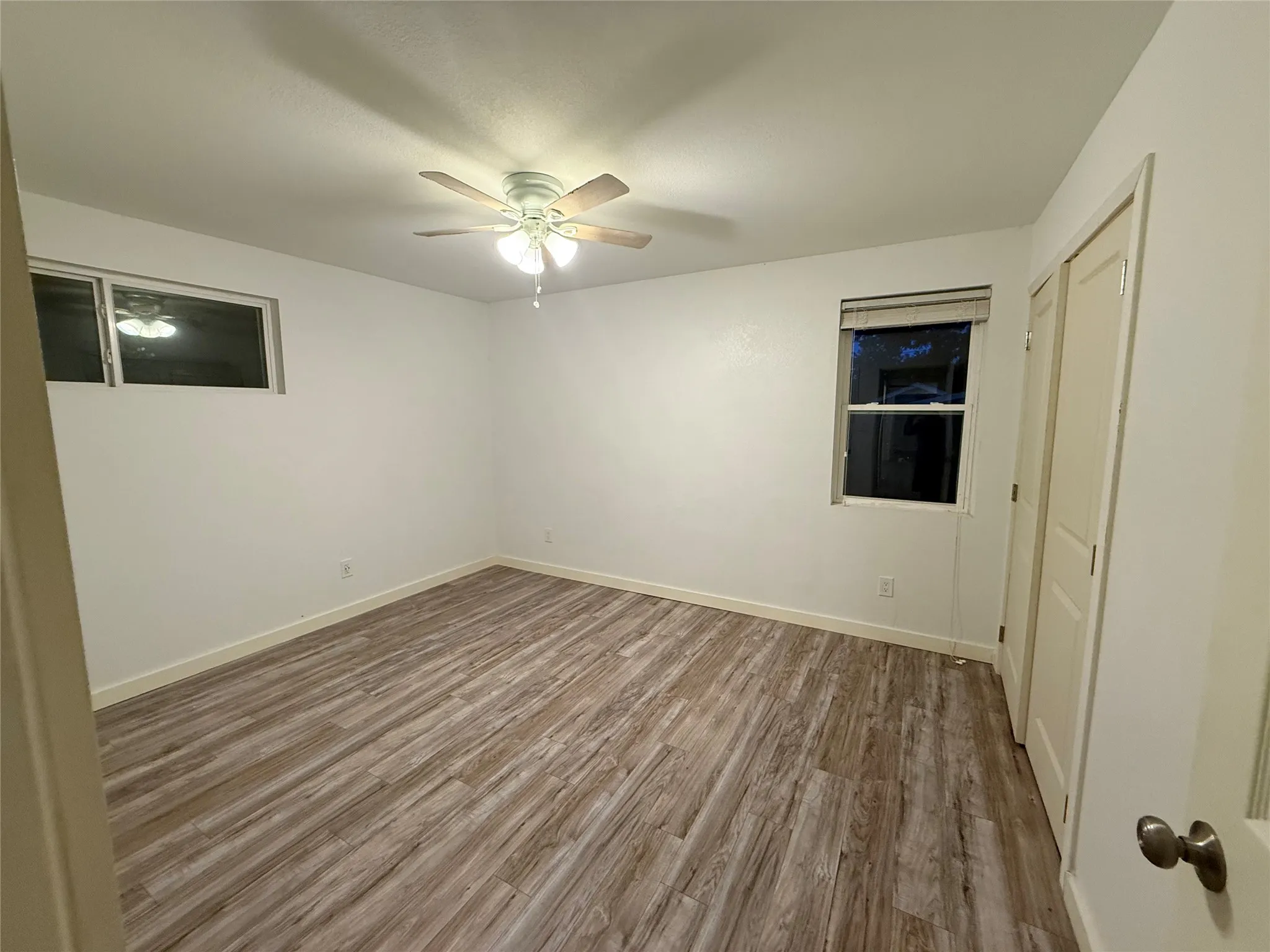 Primary bedroom which is the first bedroom at the end of the hallway with closet doors on the right closed.