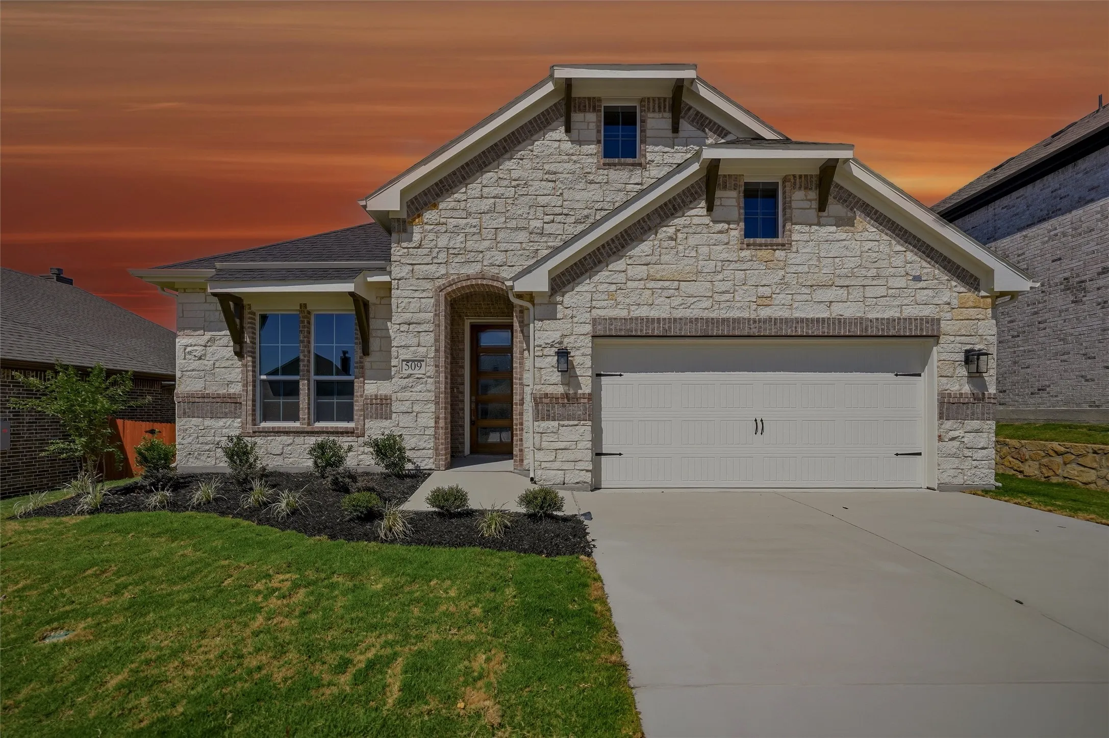 Stone veneer exterior with brick accents, wood-grain front door with glass panels, attached two-car garage, concrete driveway, and established landscaping