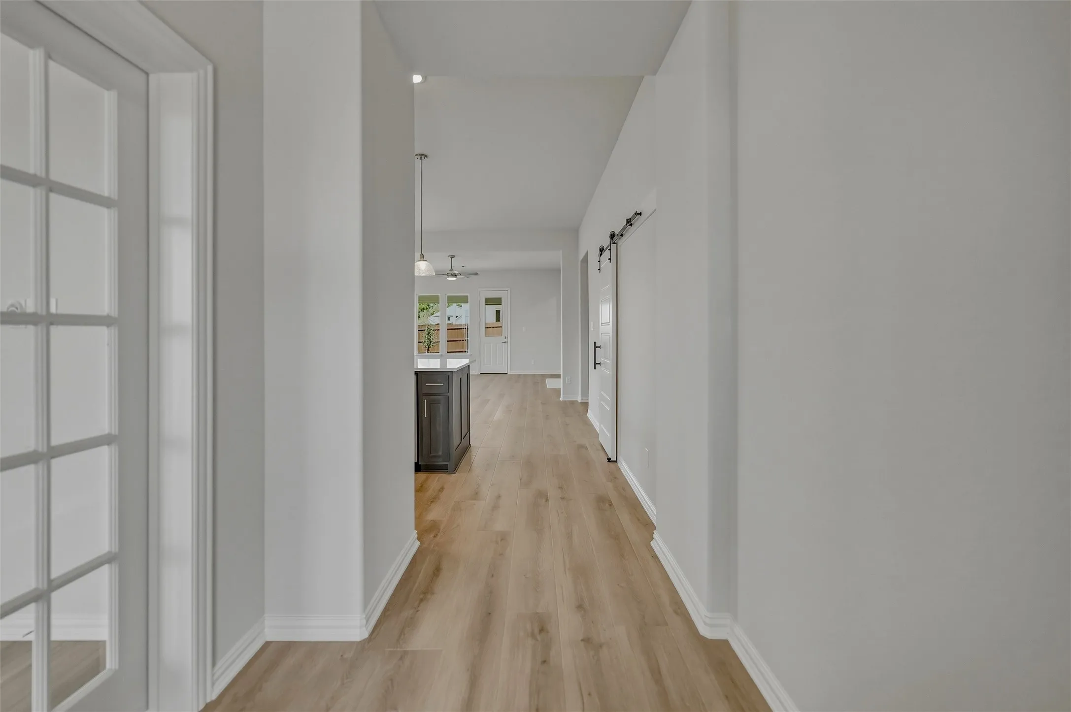 Wood-finish flooring throughout, white walls, and a barn door accent
