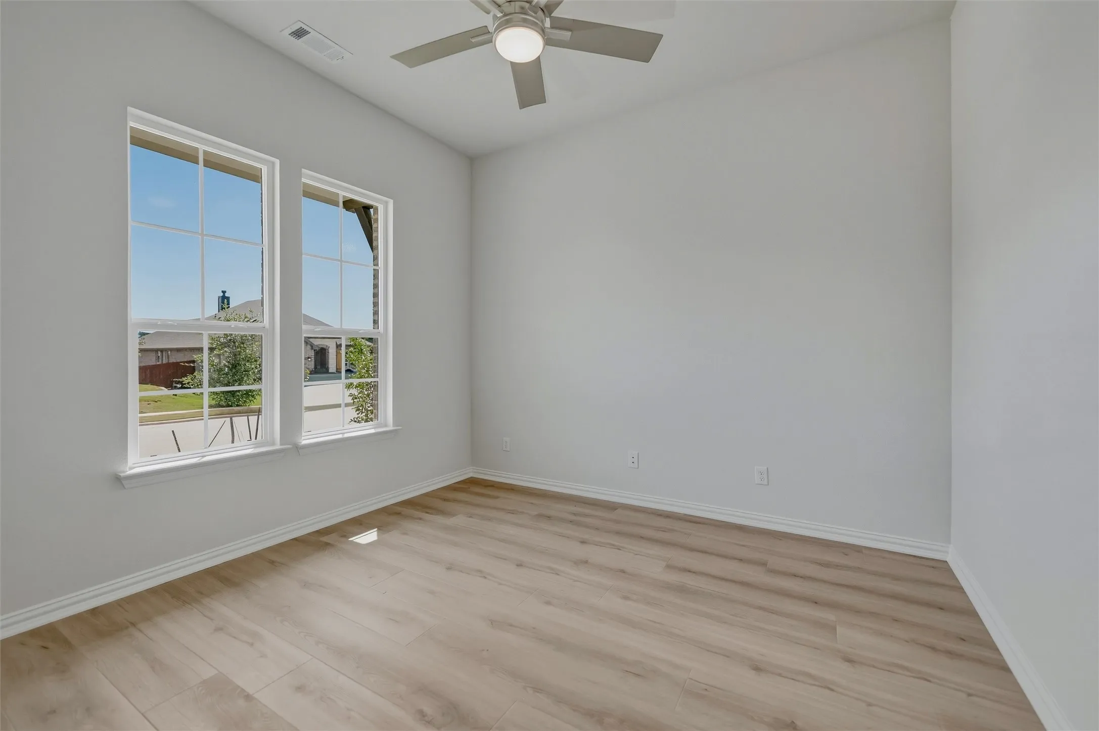 Wood-finish flooring, white trim, dual windows, and ceiling fan