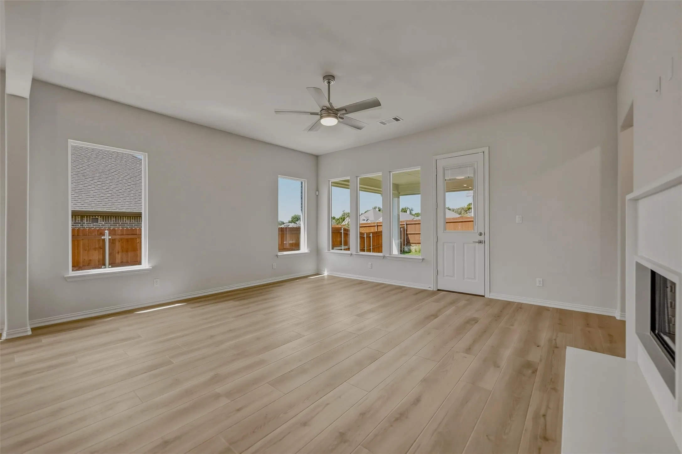 Spacious living area featuring wood-finish flooring, multiple windows, a ceiling fan, and a built-in fireplace