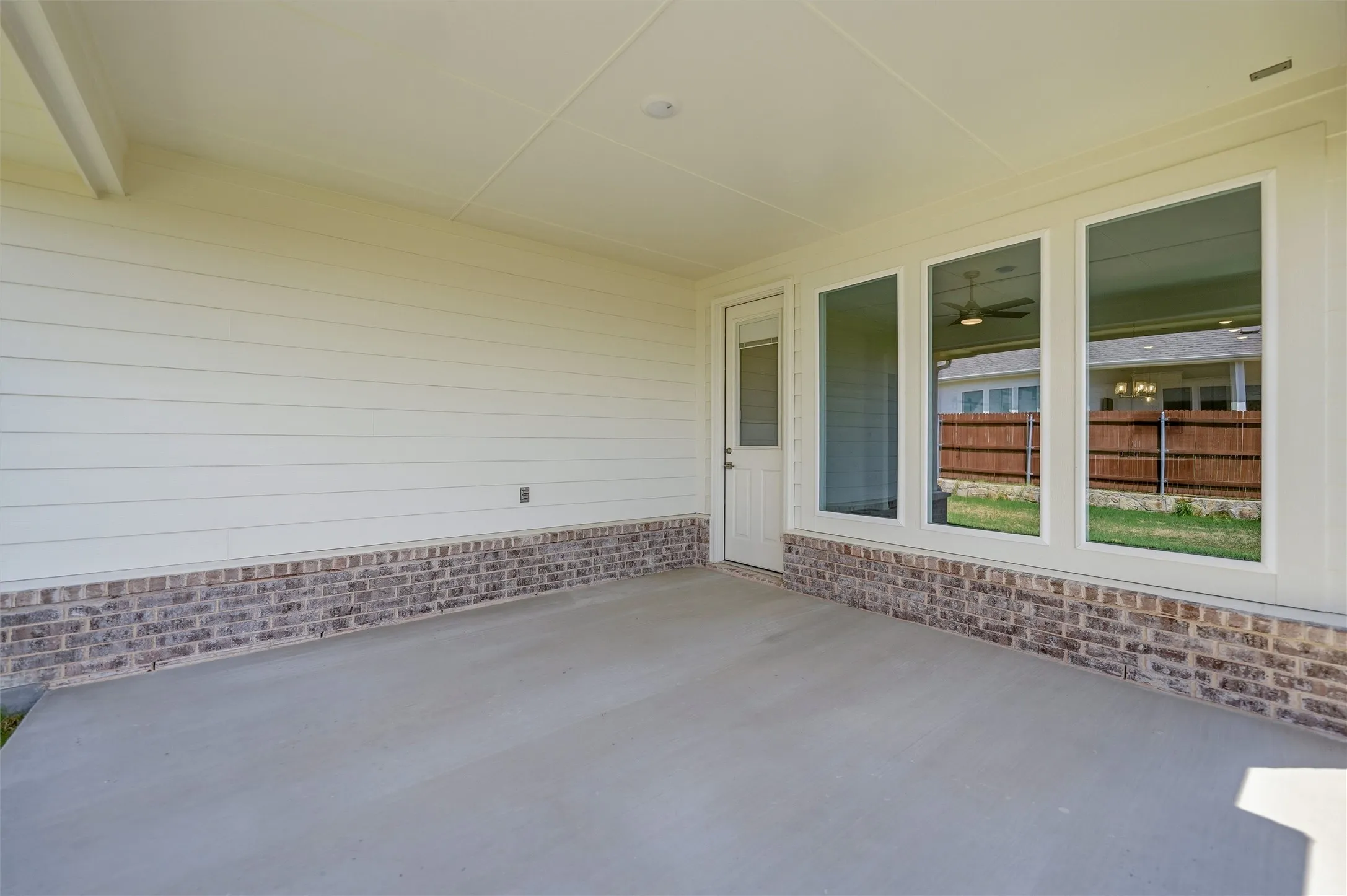 Covered patio featuring a concrete slab, brick wainscoting, and large windows