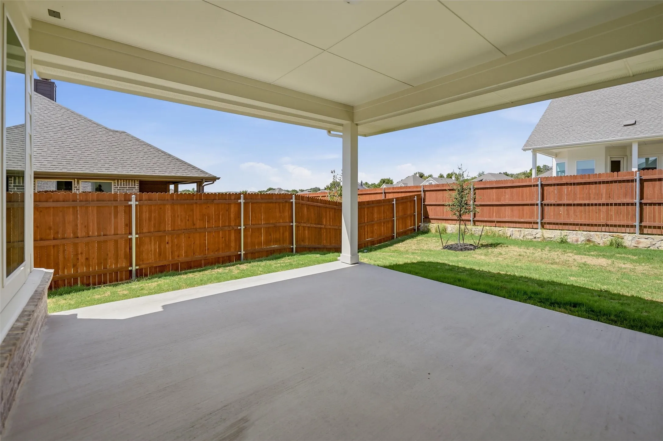 Covered patio with a concrete surface, fenced backyard, and established landscaping