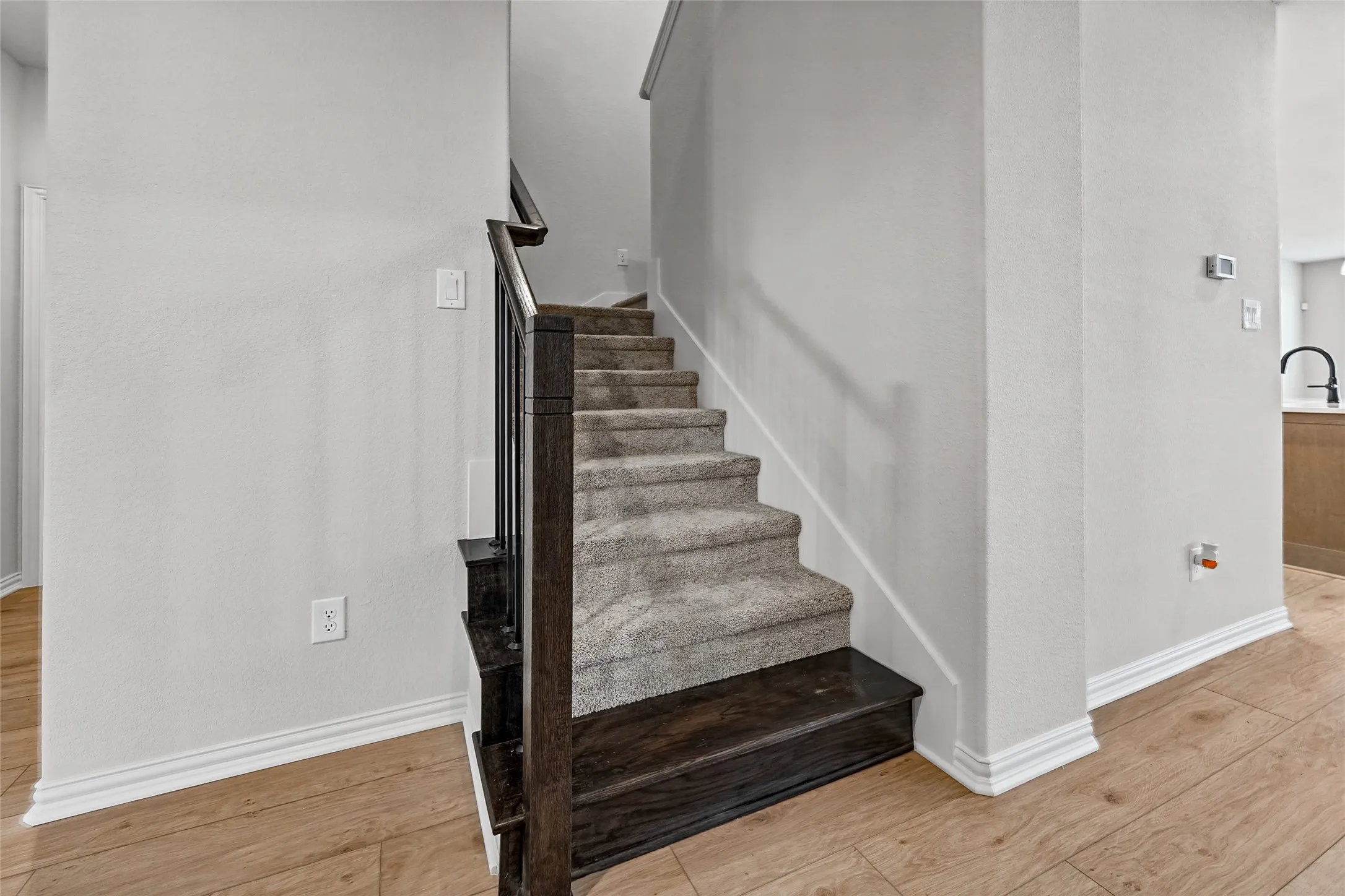 Staircase with carpeted treads and dark wood-finish newel post and handrail