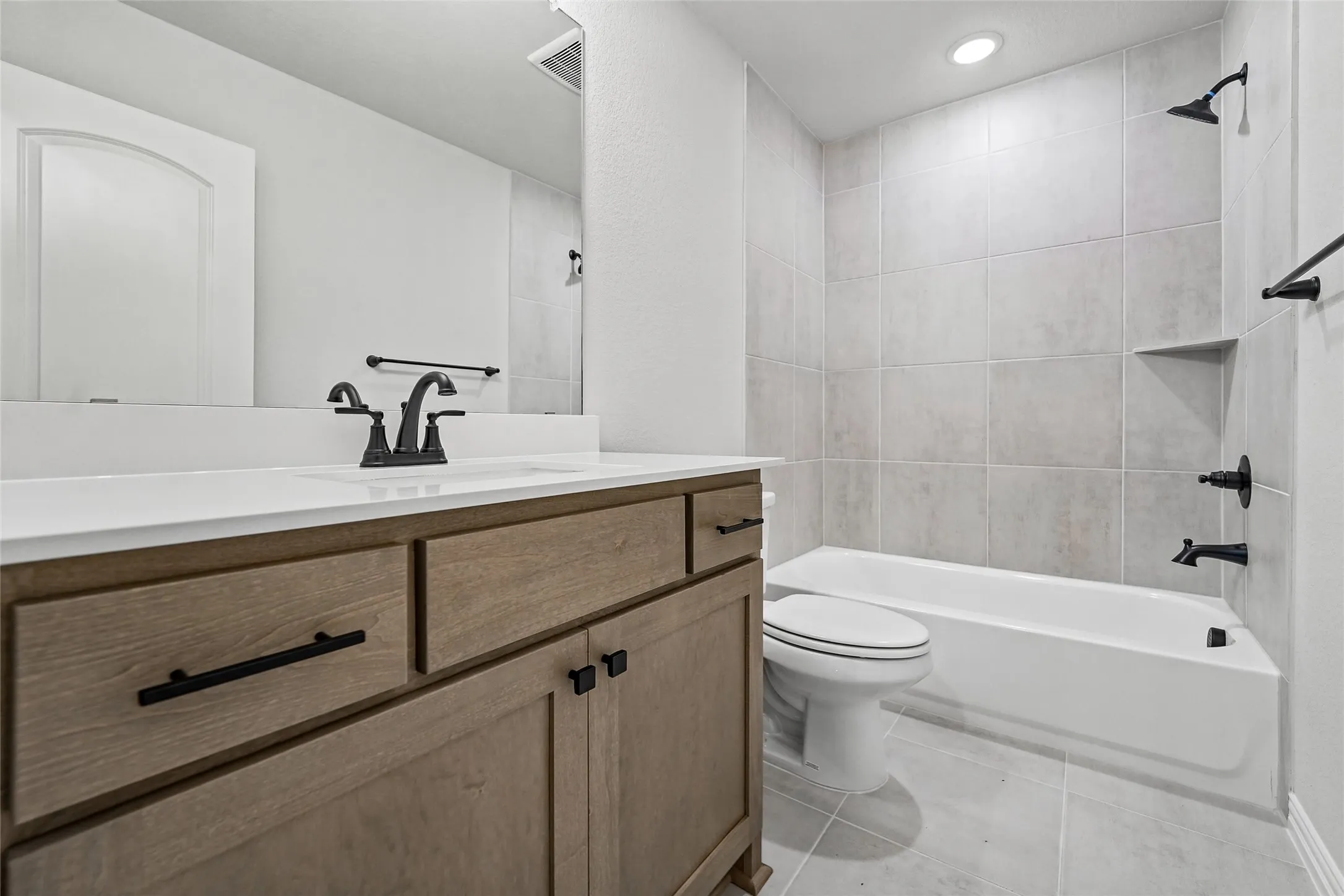 Wood-finish vanity with a white countertop and black hardware