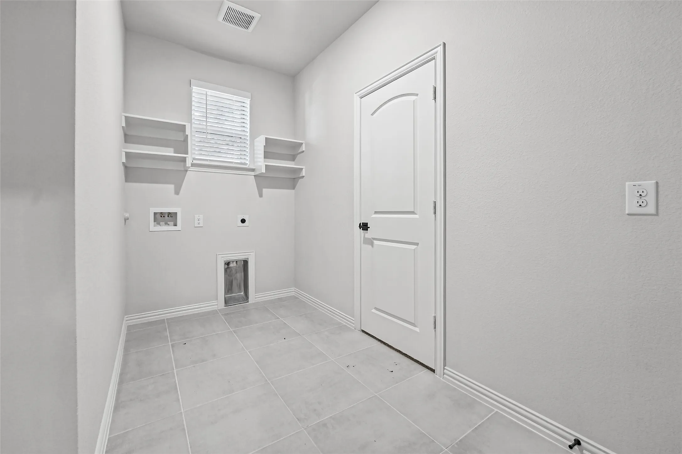 Utility room with tile flooring, built-in shelving, and a window for natural light