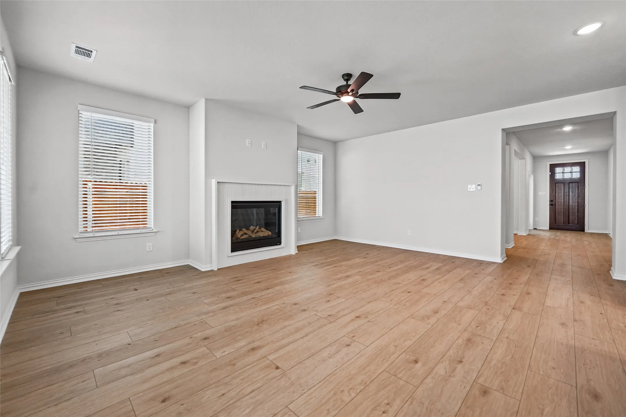 Spacious interior featuring wood-finish flooring, a contemporary fireplace, and a ceiling fan