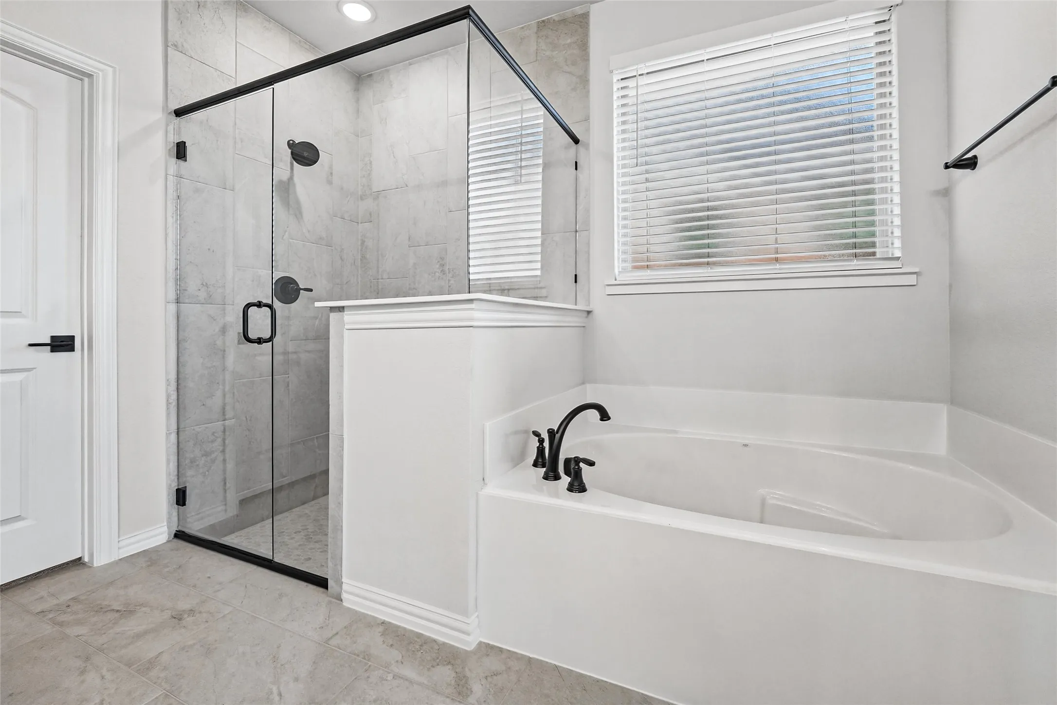 Frameless glass shower with matte black hardware, tiled shower surround, recessed lighting, built-in soaking tub with matte black fixtures, and tiled flooring