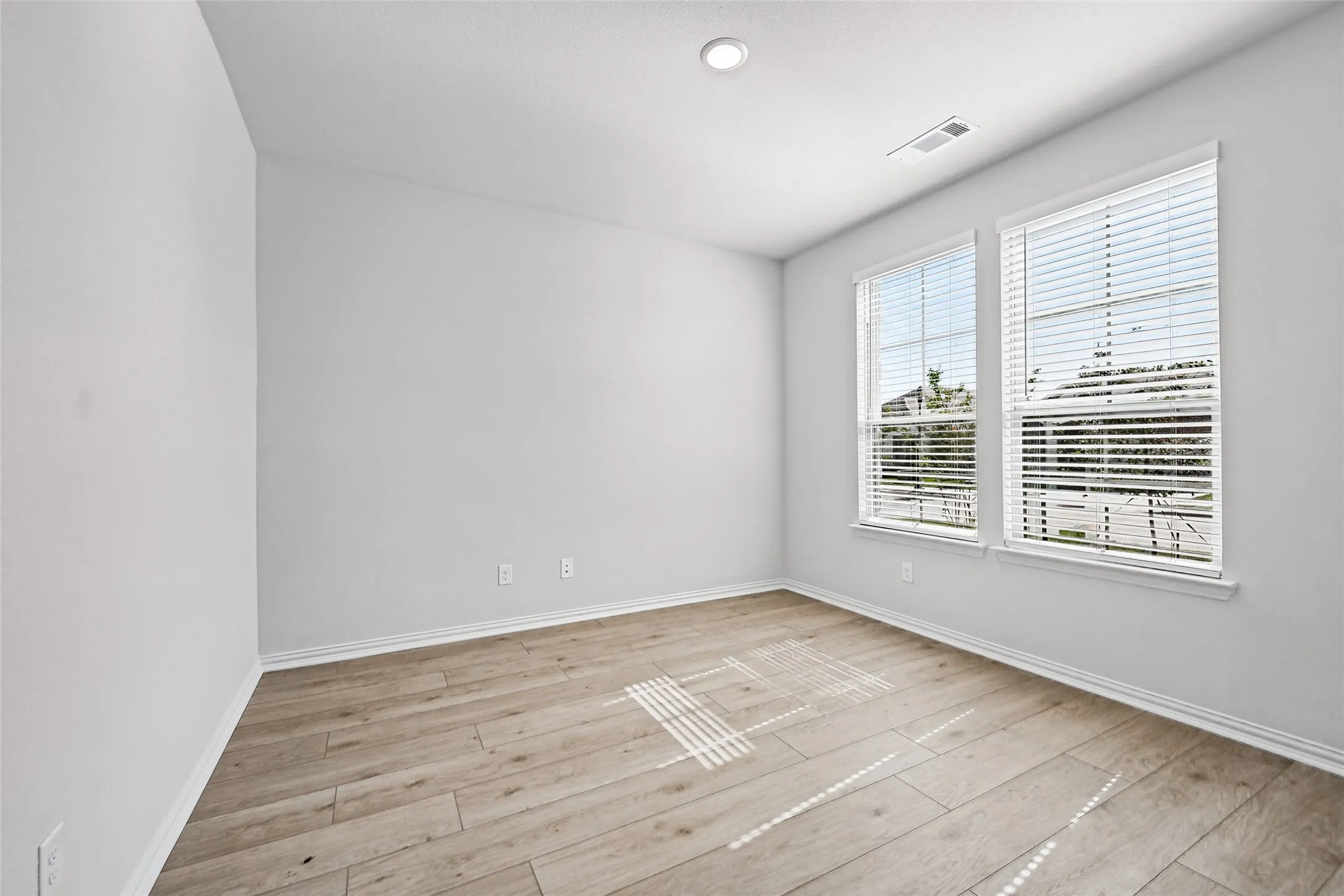 Wood-finish flooring, recessed lighting, and two windows with blinds