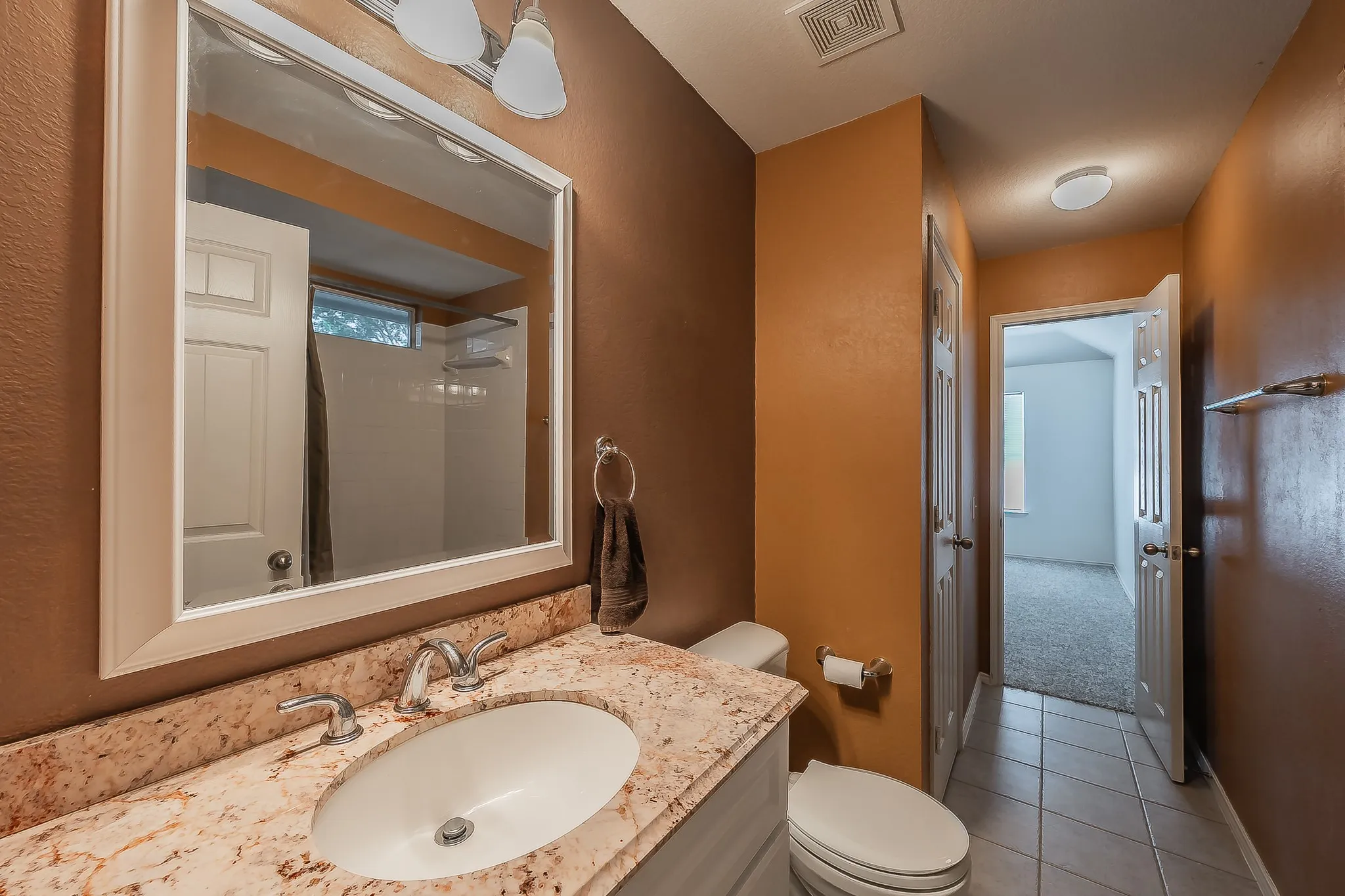 Bathroom vanity featuring a polished stone countertop, undermount sink, and dual-handle faucet