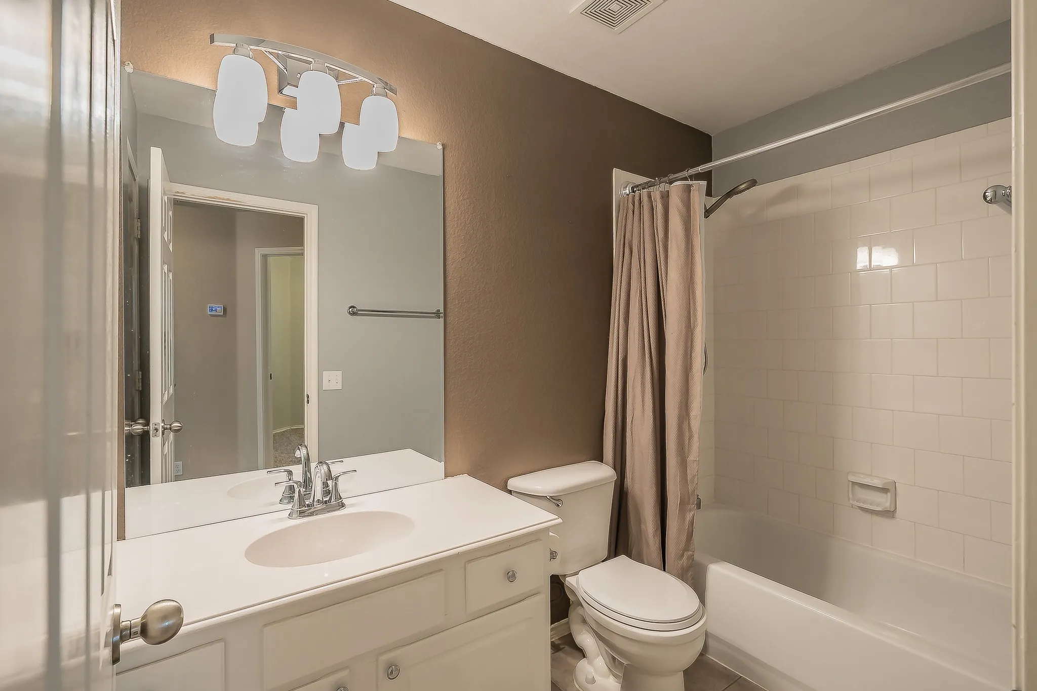 Bathroom featuring a white vanity with an integrated sink, chrome faucet, and a large mirror