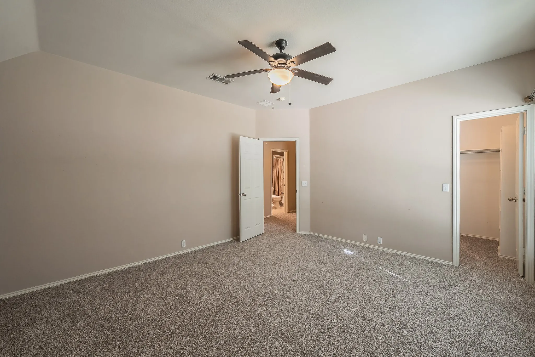 Carpeted room featuring a ceiling fan with light fixture, neutral wall paint, white trim, and two doorways