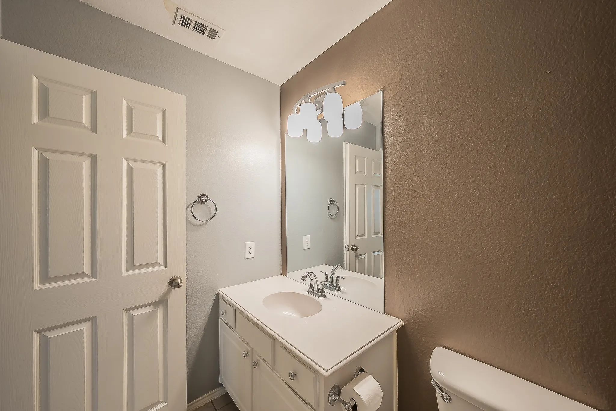 Bathroom featuring a white vanity with integrated sink, chrome faucet, and mirrored medicine cabinet