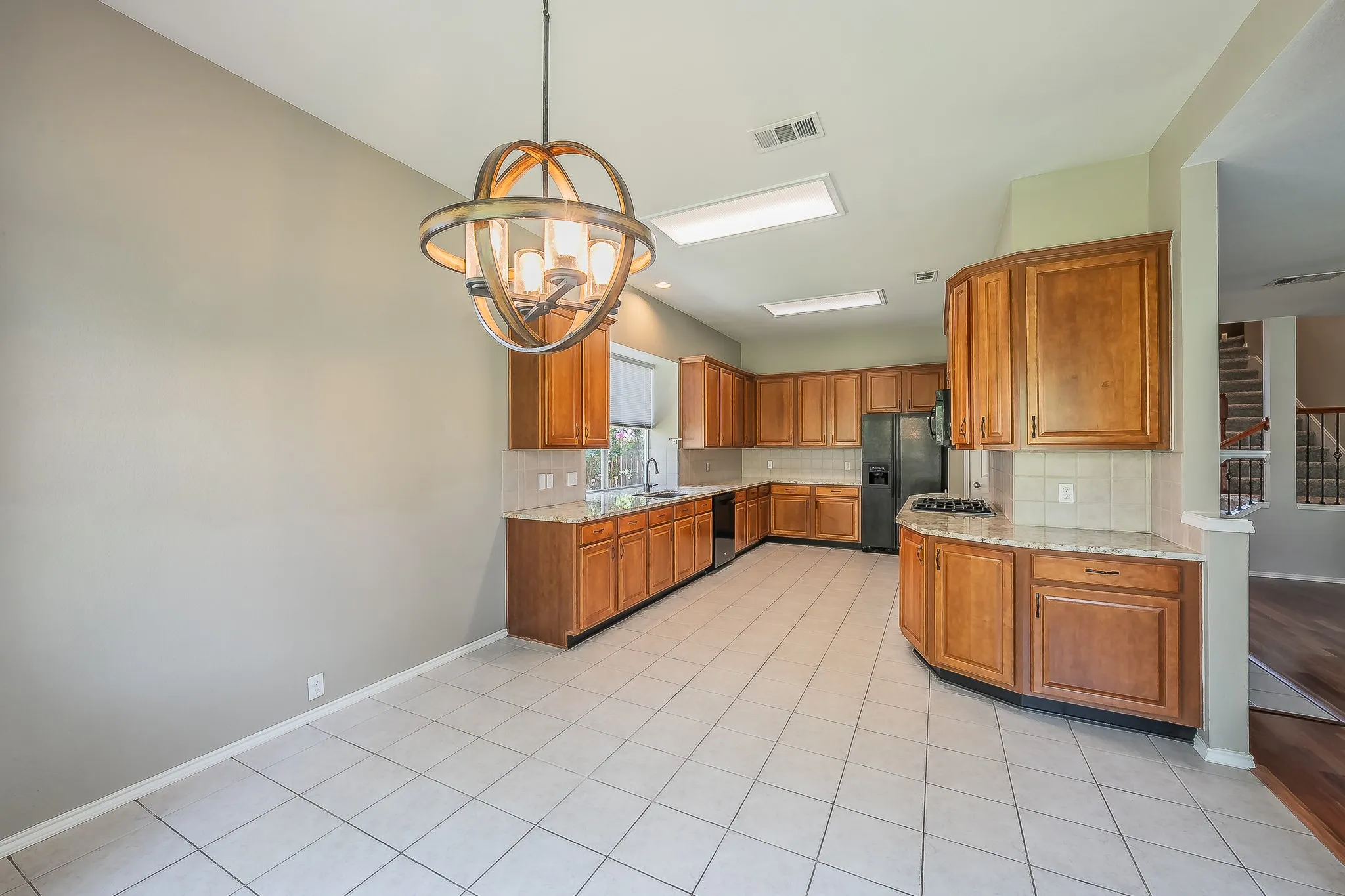 Spacious kitchen featuring extensive wood cabinetry, light-toned countertops, and a white tile backsplash
