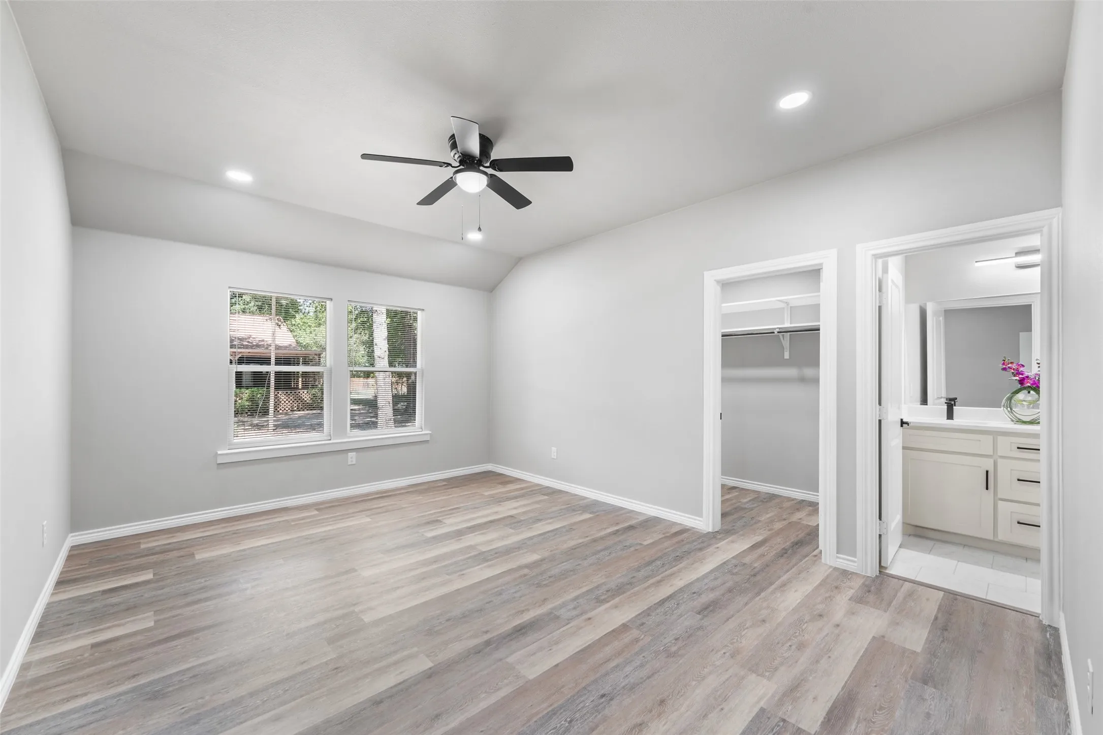 Spacious room featuring wood-finish flooring, vaulted ceilings, and recessed lighting