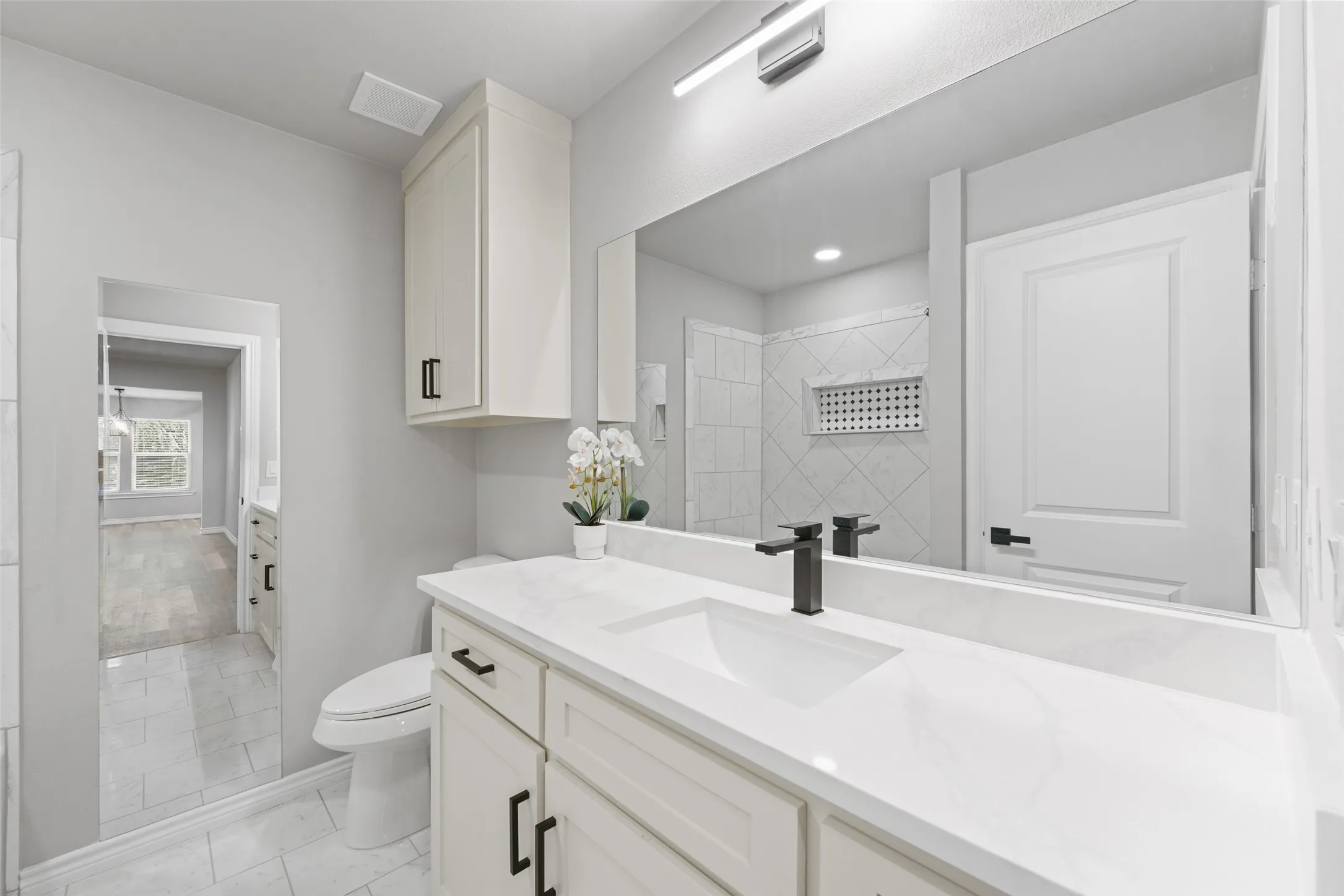 Bathroom vanity featuring a single basin, white countertop, and matte black faucet