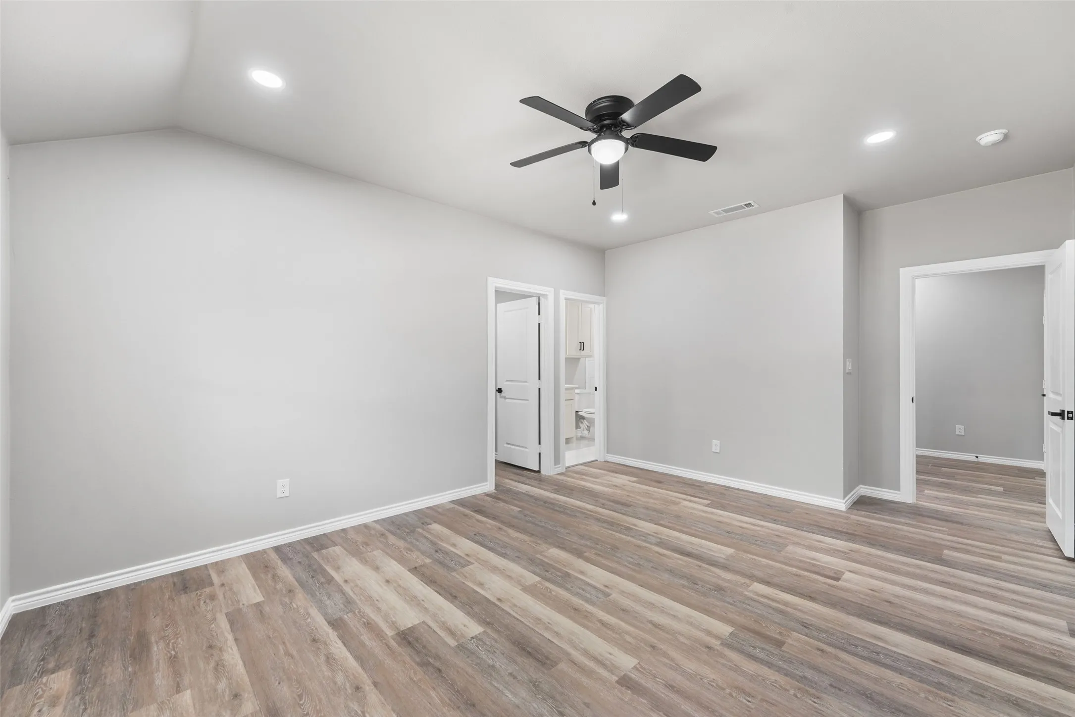 Spacious interior featuring wood-finish flooring, light gray wall tones, and recessed lighting