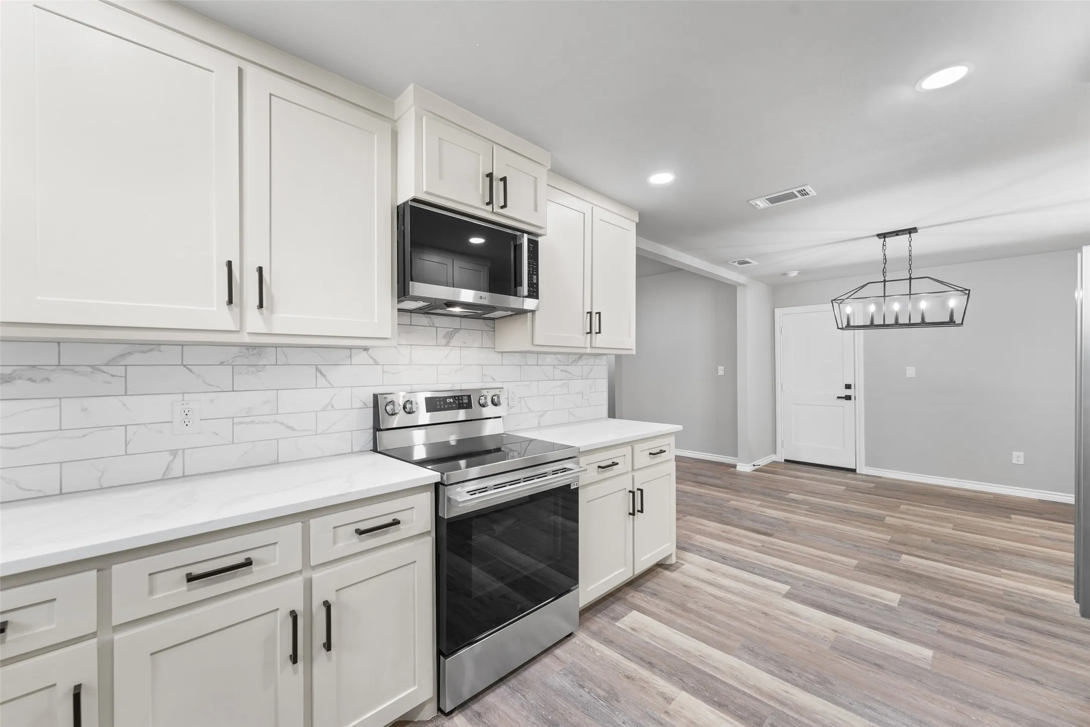 Modern kitchen featuring white shaker cabinetry, stainless steel appliances, and light countertops