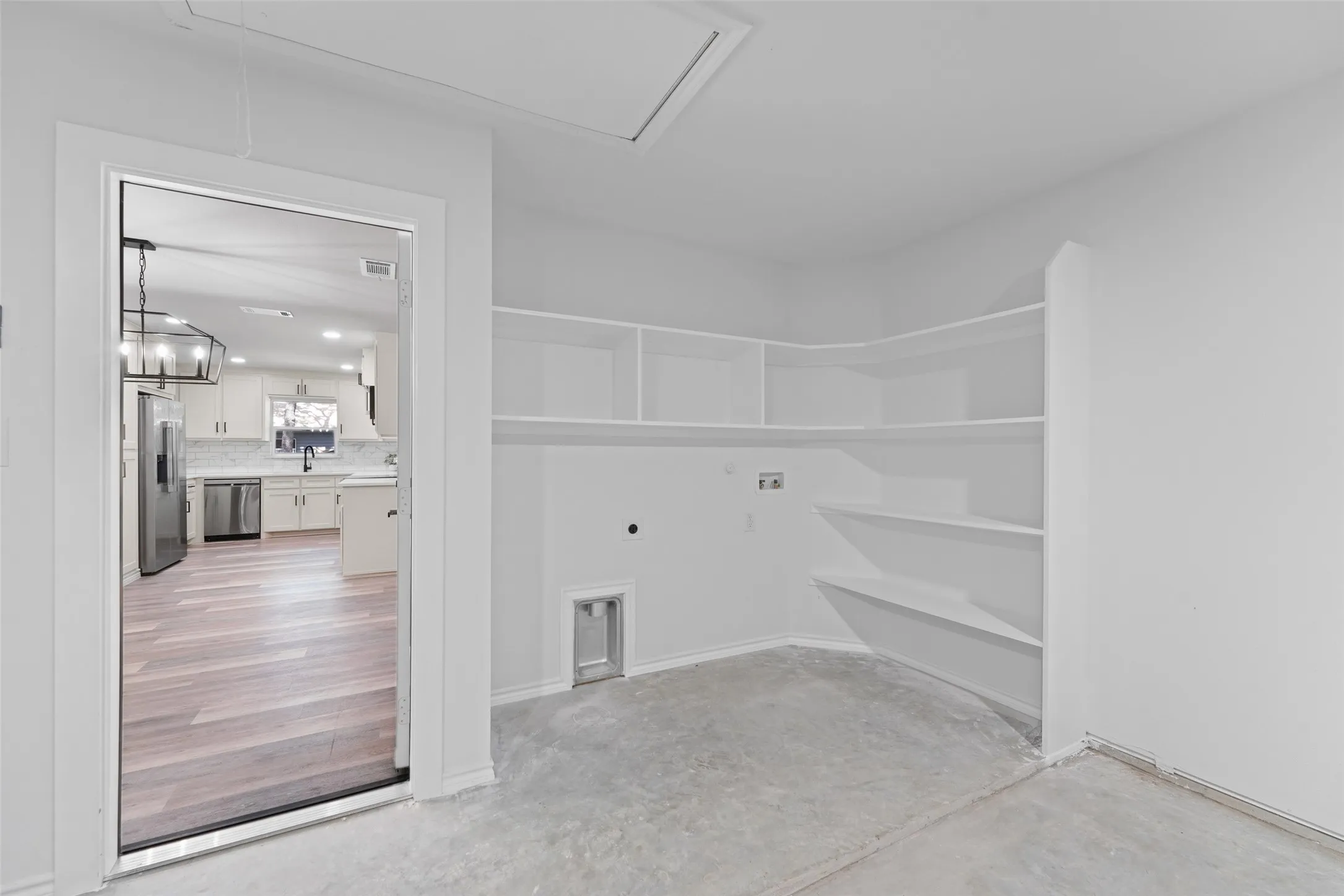 Utility room with concrete flooring, built-in shelving, and laundry hookups