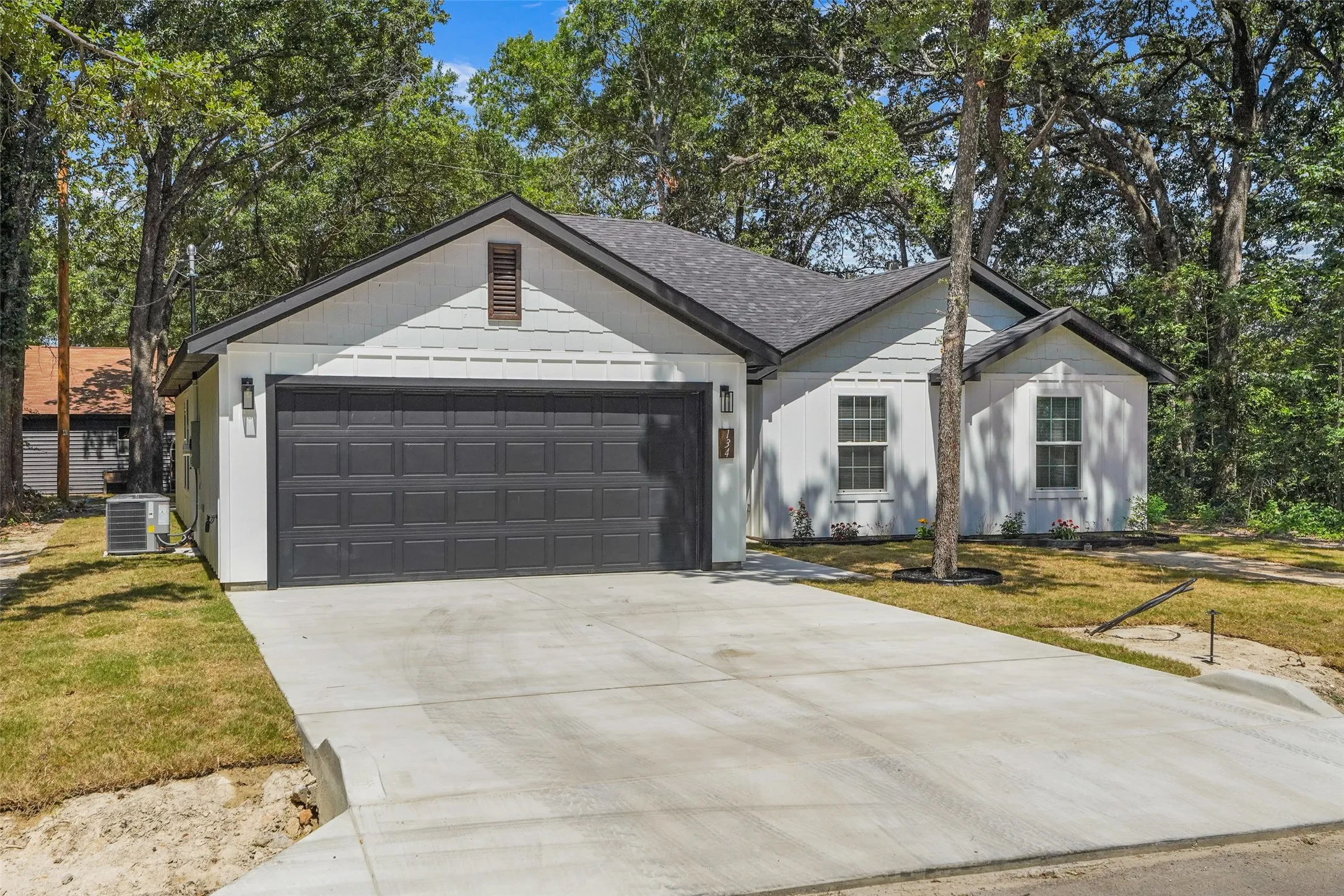 White siding exterior with a dark shingle roof and a dark paneled garage door