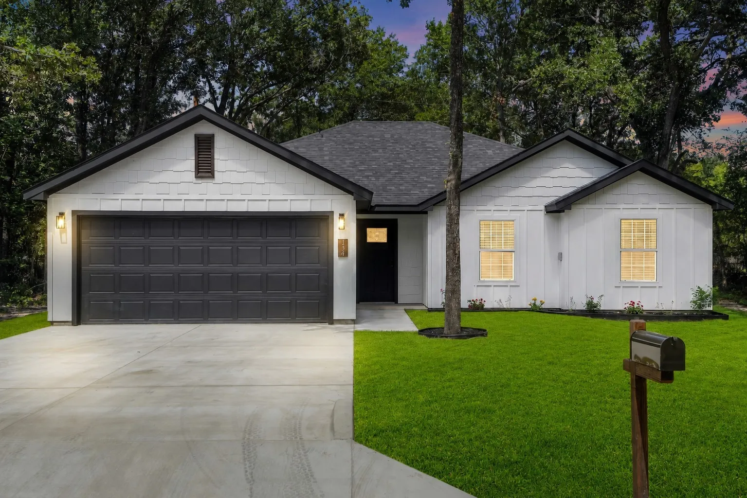 Contemporary single-story residence featuring white siding, a dark roof, and a two-car garage