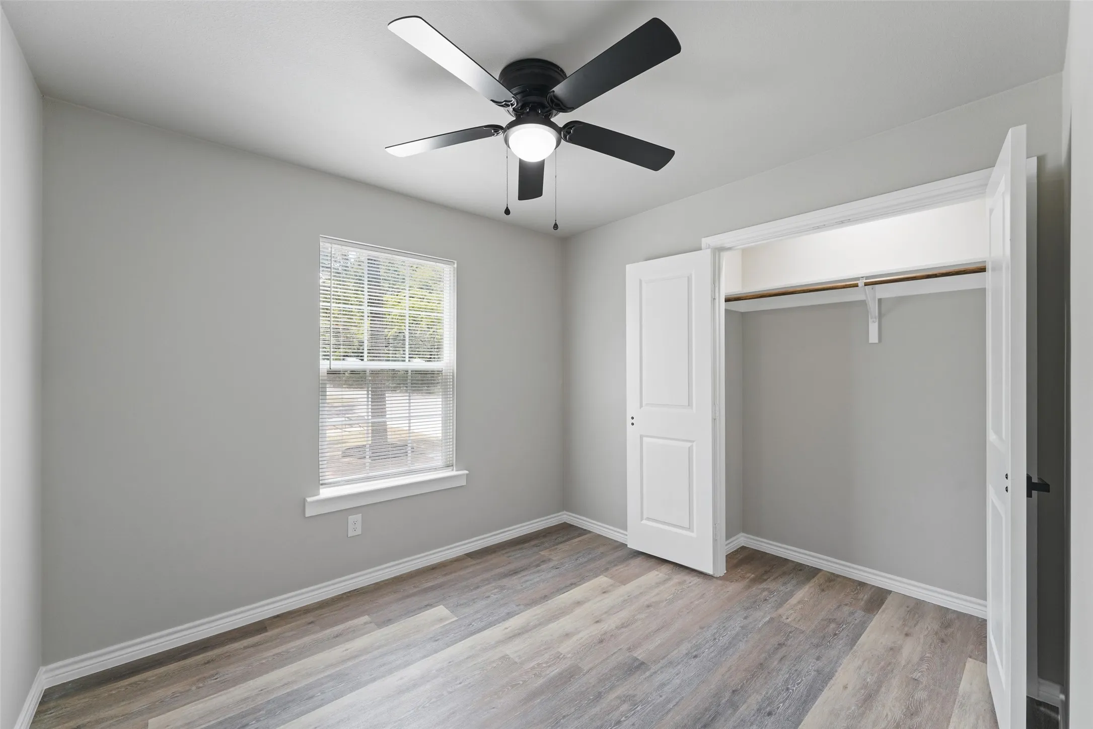 Room featuring wood-finish flooring, light grey wall paint, and white baseboards