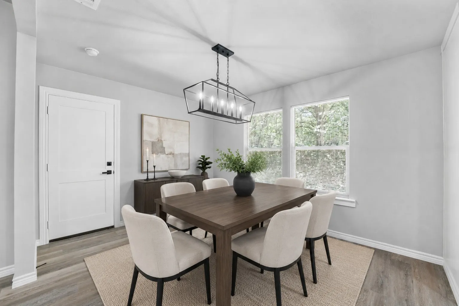 Dining area with wood-finish flooring, light grey walls, and white baseboards