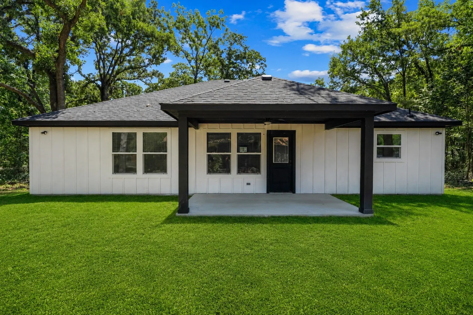 Rear exterior with a covered concrete patio and a black shingle roof
