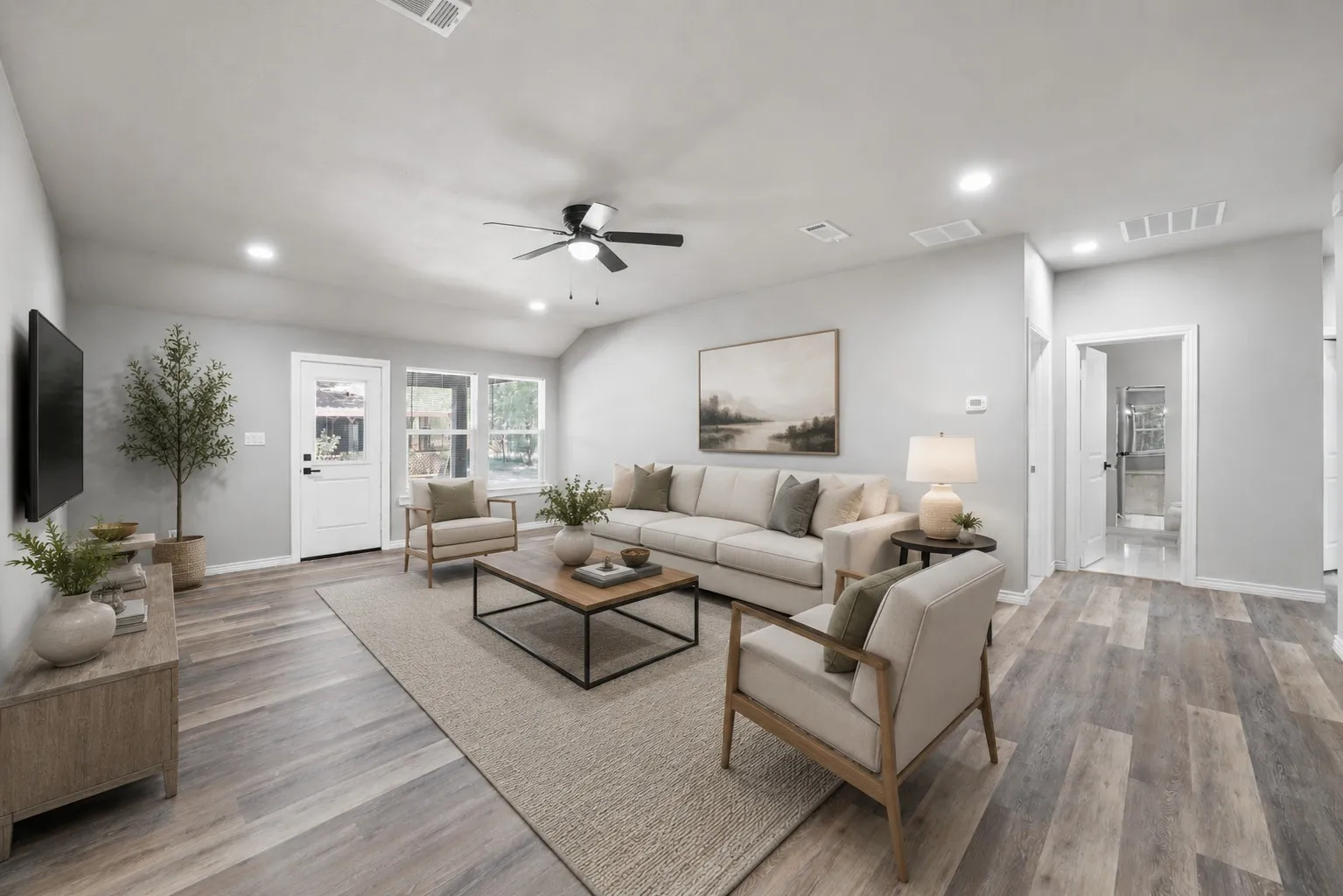 Spacious living area featuring wood-finish flooring, light gray wall tones, and recessed lighting