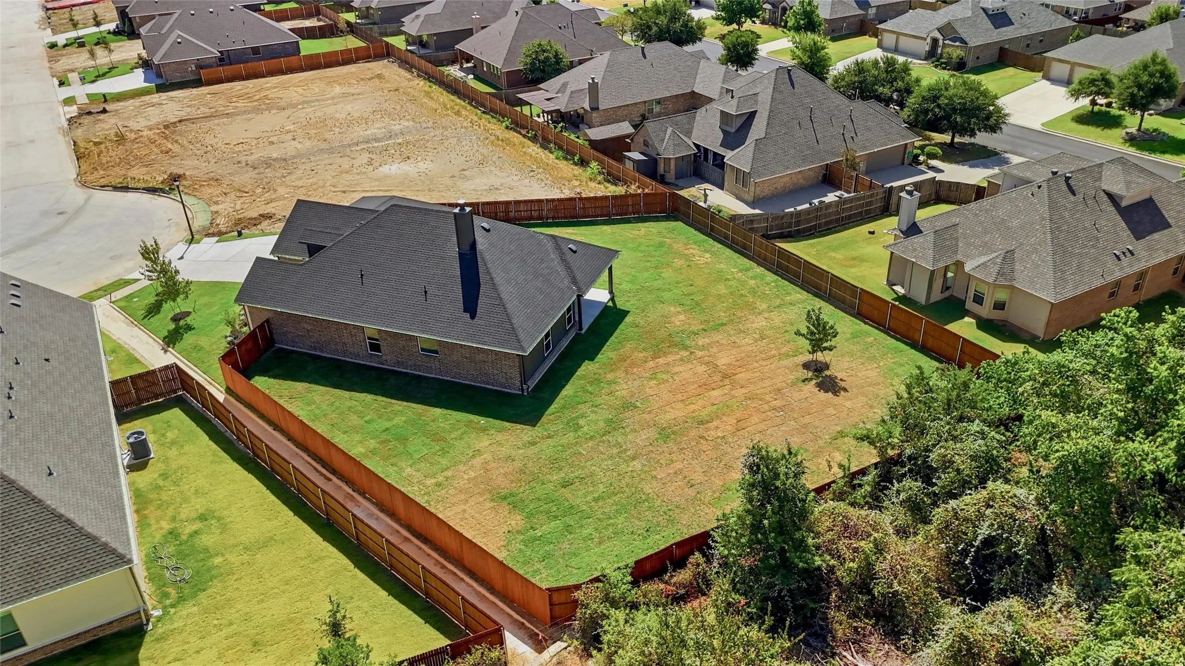Expansive backyard with a manicured lawn, complete with a covered patio, and surrounded by a privacy fence