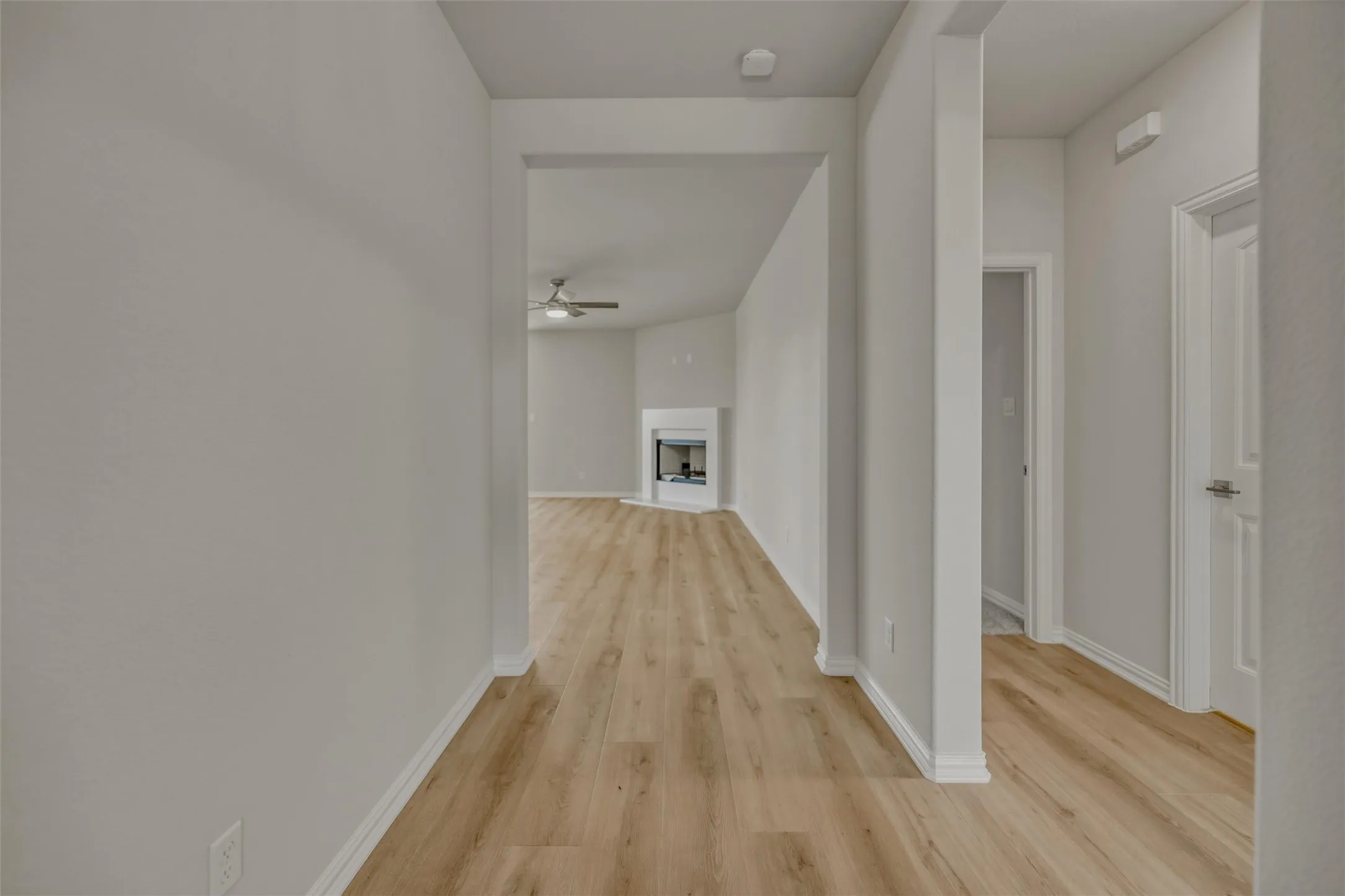 Wood-finish flooring throughout, white baseboards, and a contemporary ceiling fan