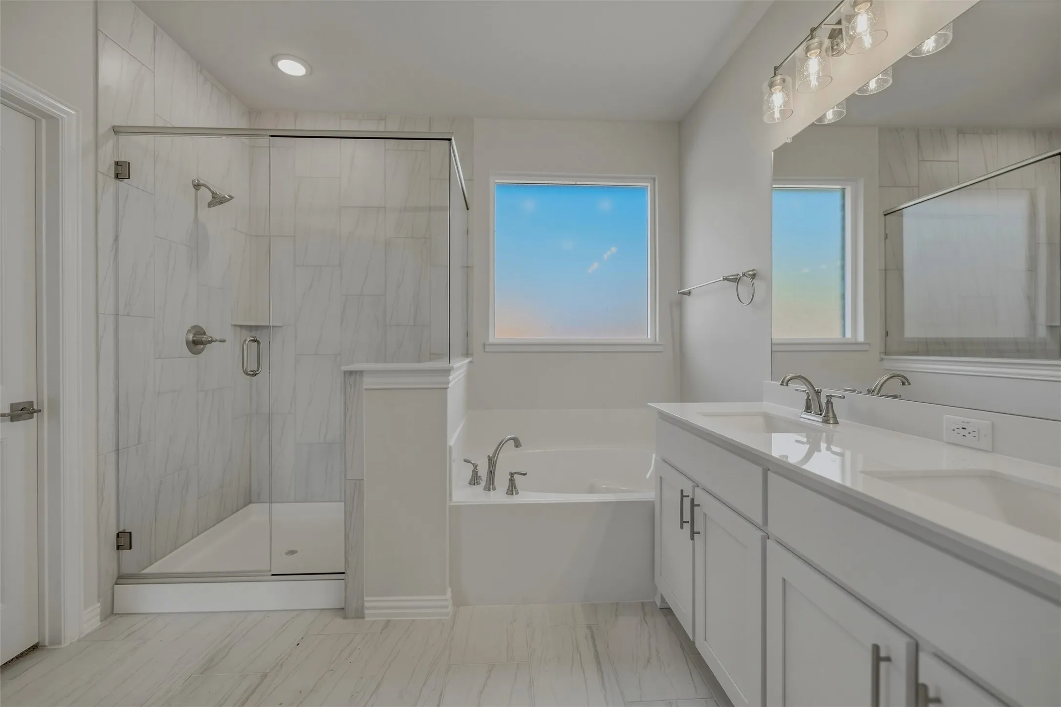 Walk-in shower with clear glass enclosure and tile surround