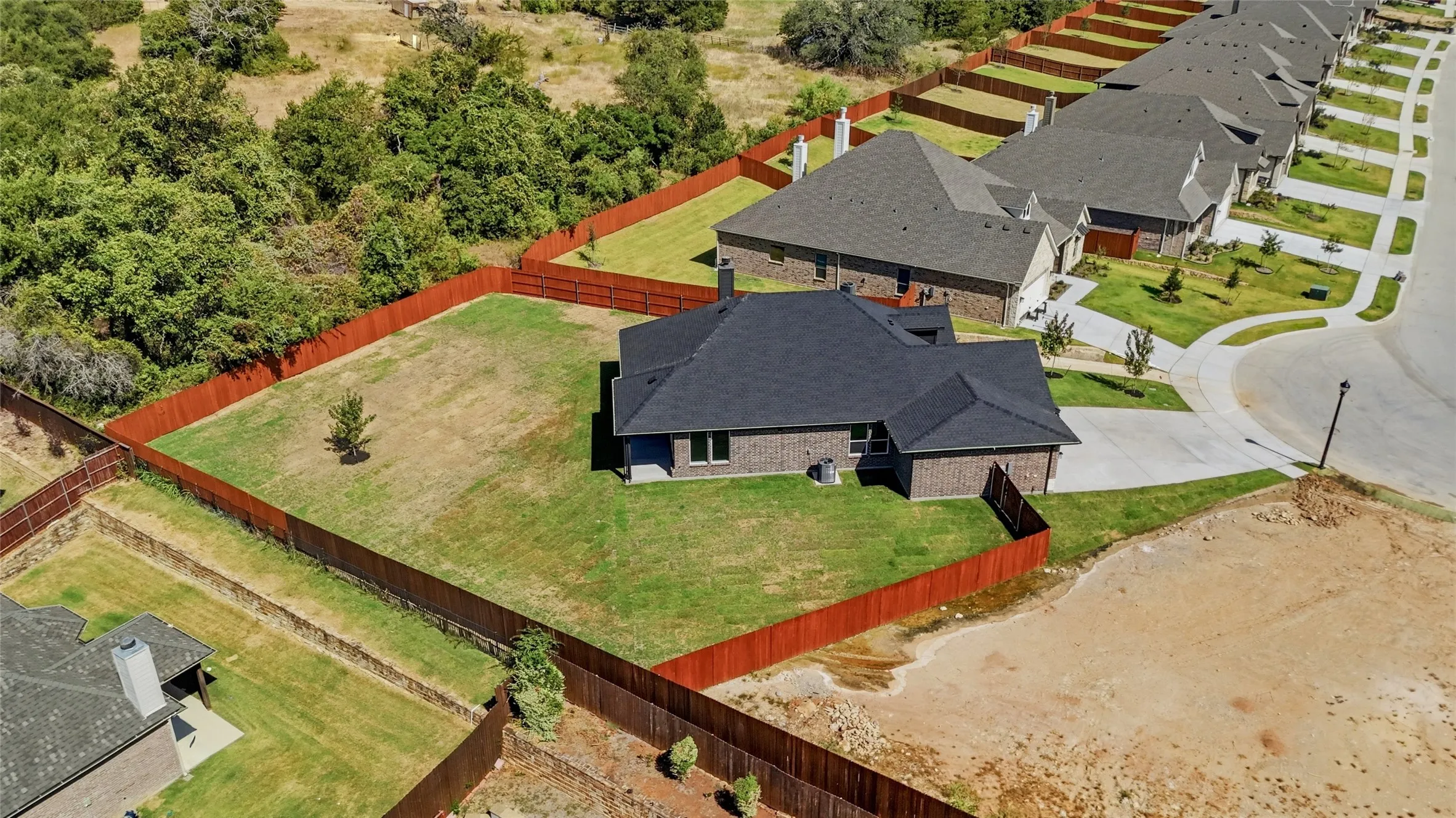 Brick exterior residence with a dark shingle roof, a fenced backyard, and a concrete driveway