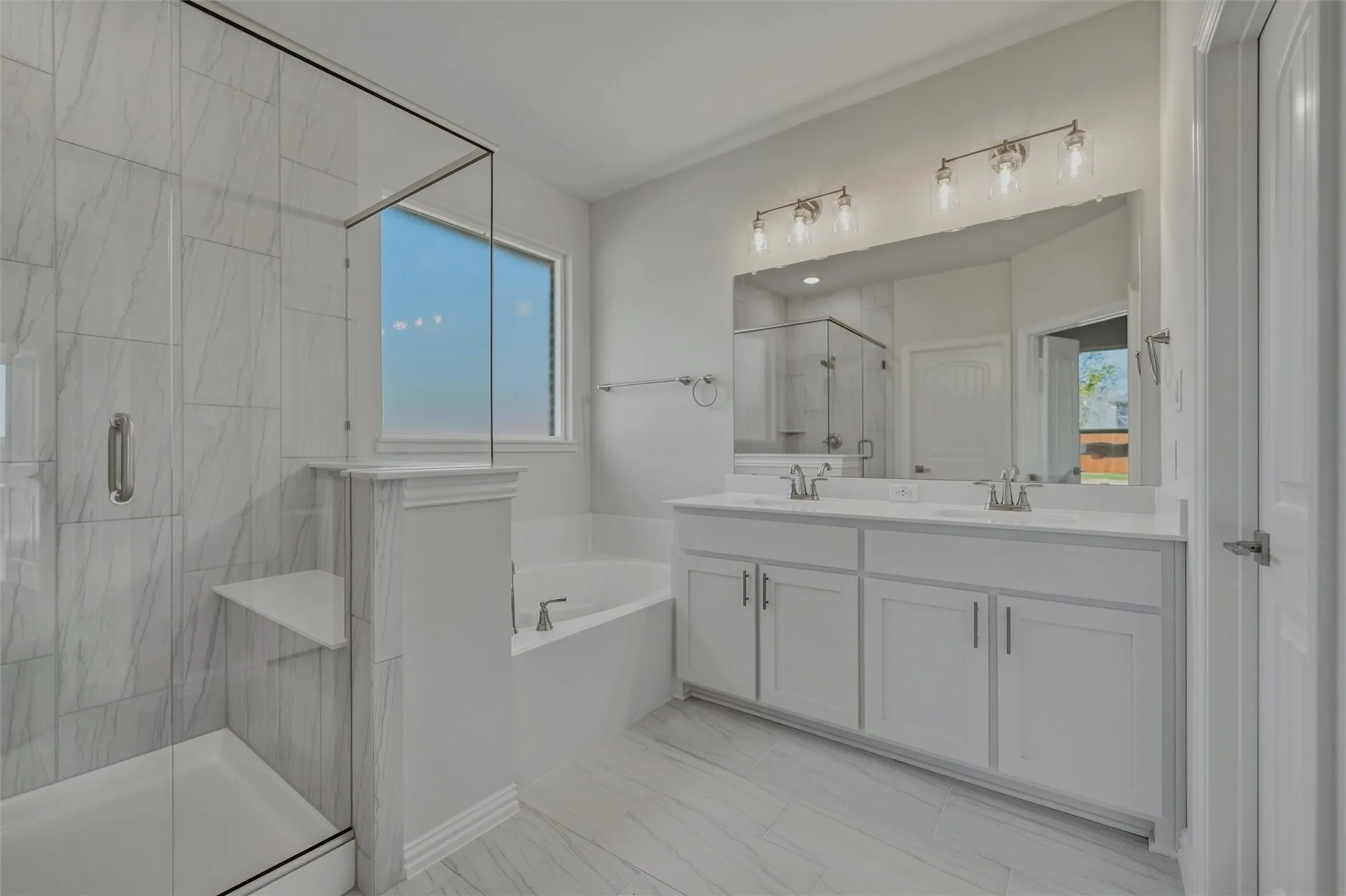 Spacious bathroom featuring a glass-enclosed shower with a built-in bench, a separate soaking tub, and a dual-sink vanity with white cabinetry and a large mirror