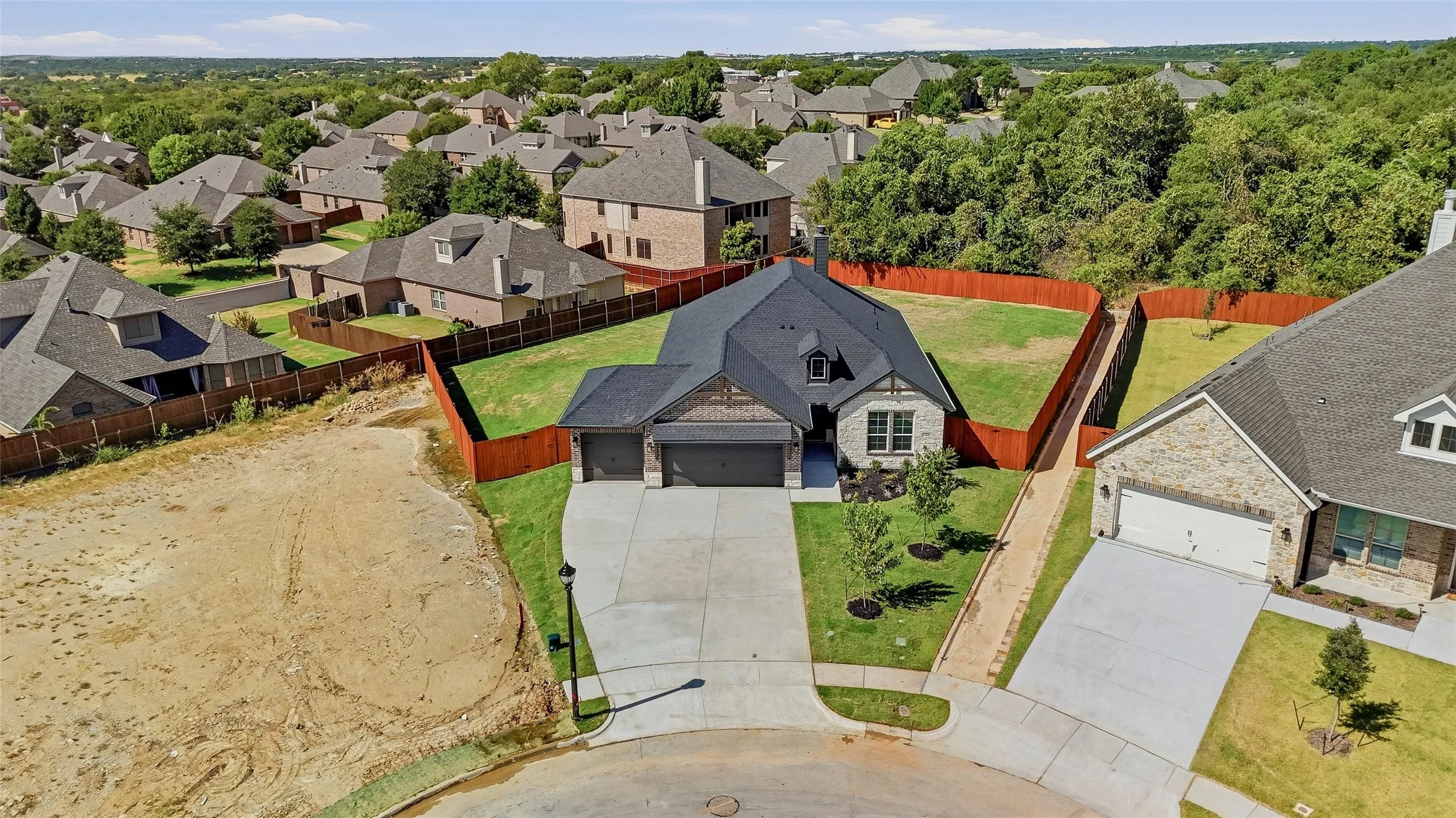 Stone and brick exterior with a dark roof, attached two-car garage, and a concrete driveway