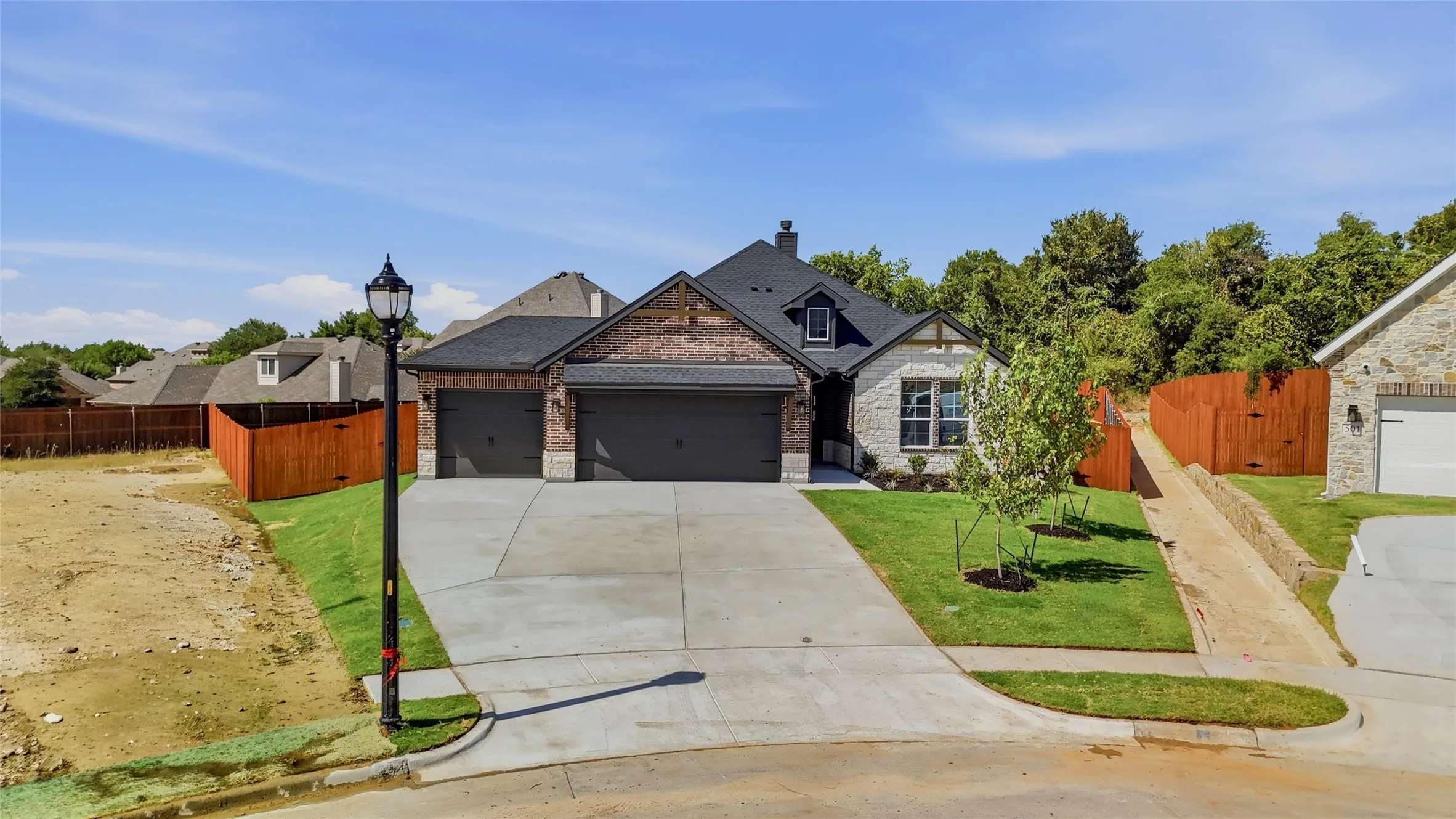 Brick and stone exterior with dark trim accents, a two-car garage, and a concrete driveway