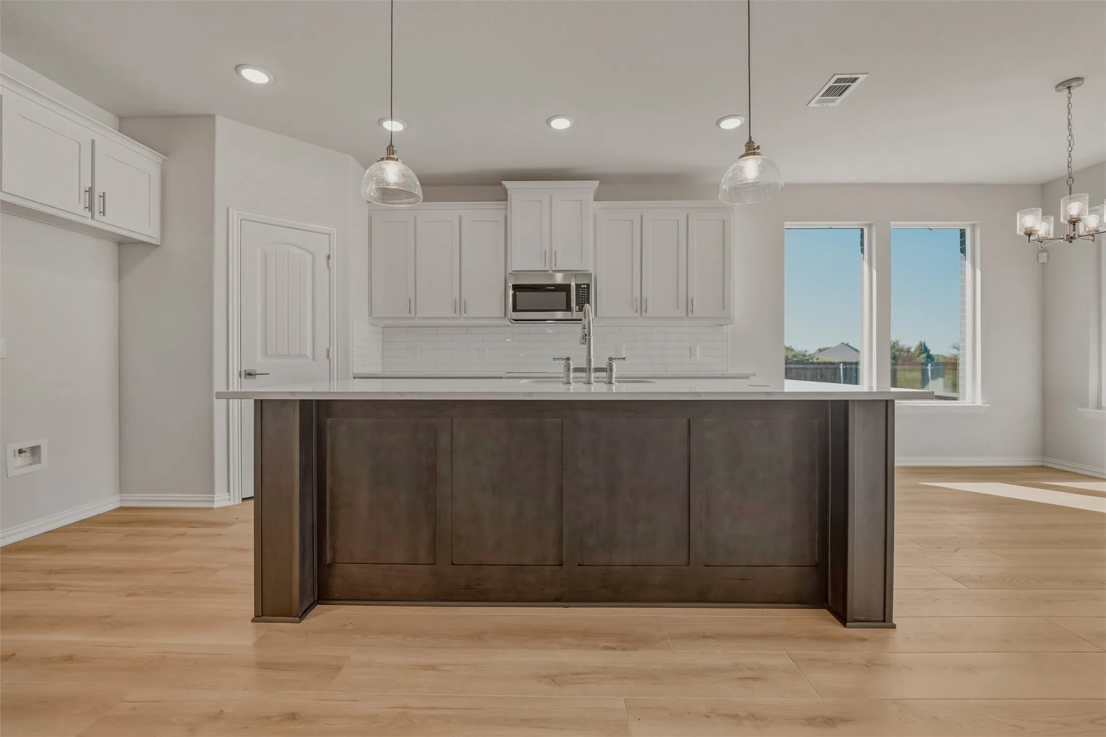 Kitchen featuring a central island, white shaker cabinetry, stainless steel appliances, and wood-finish flooring