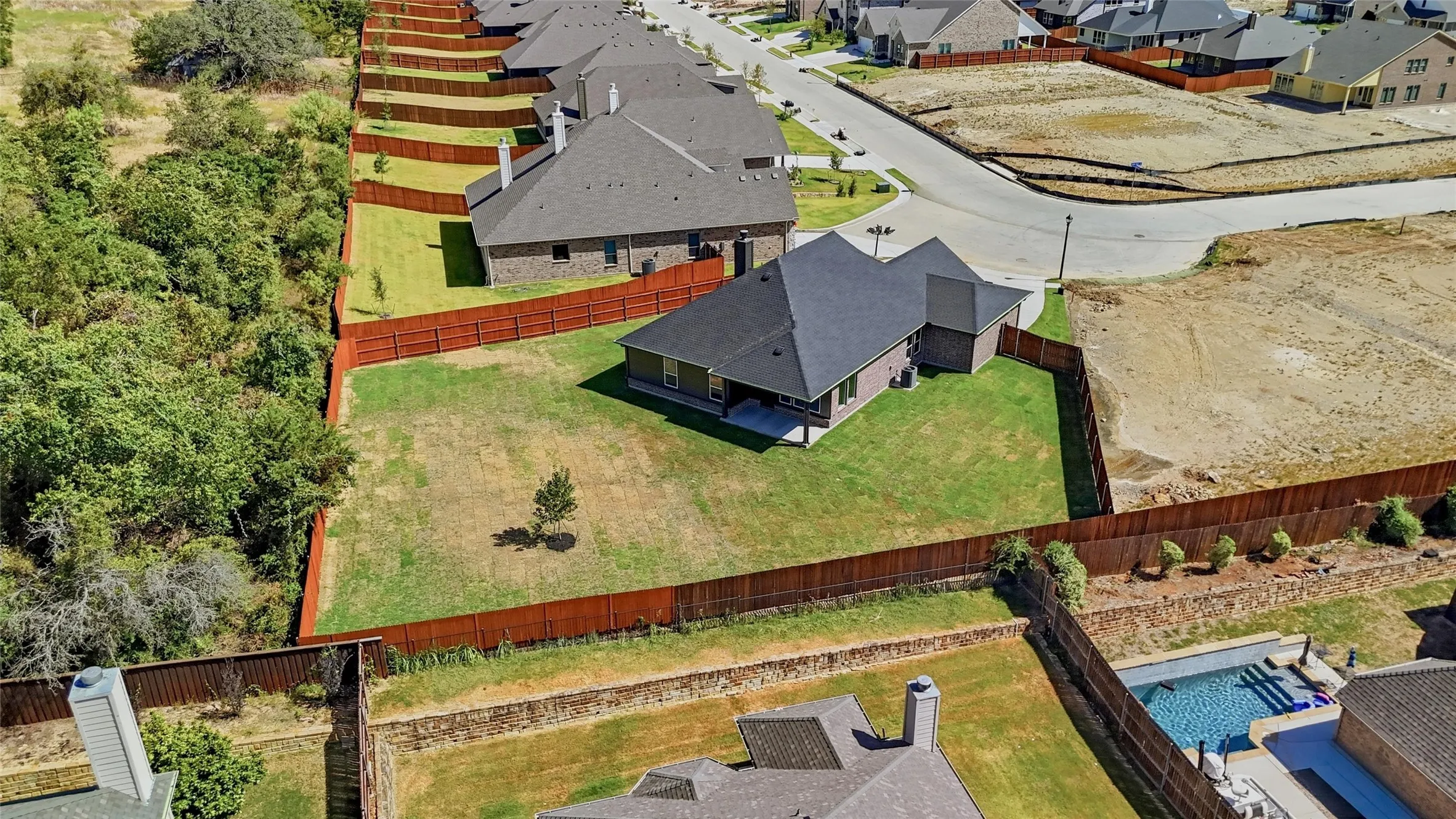 Fenced backyard with a young tree and manicured lawn