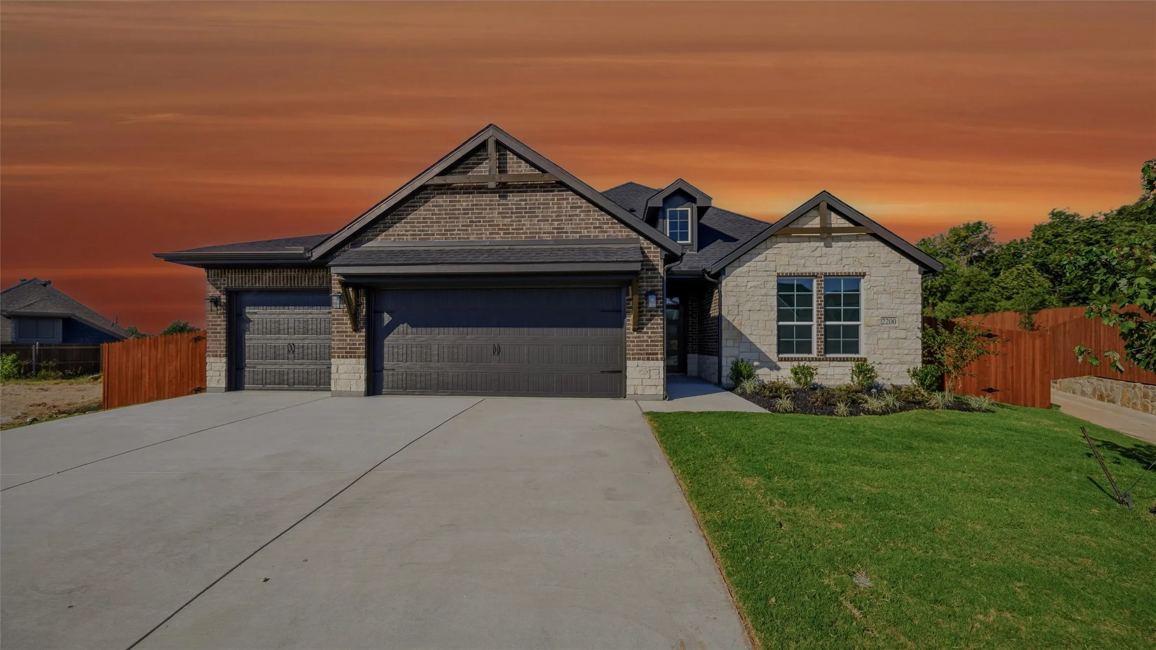 Brick and stone exterior with architectural gables, concrete driveway, and attached two-car garage