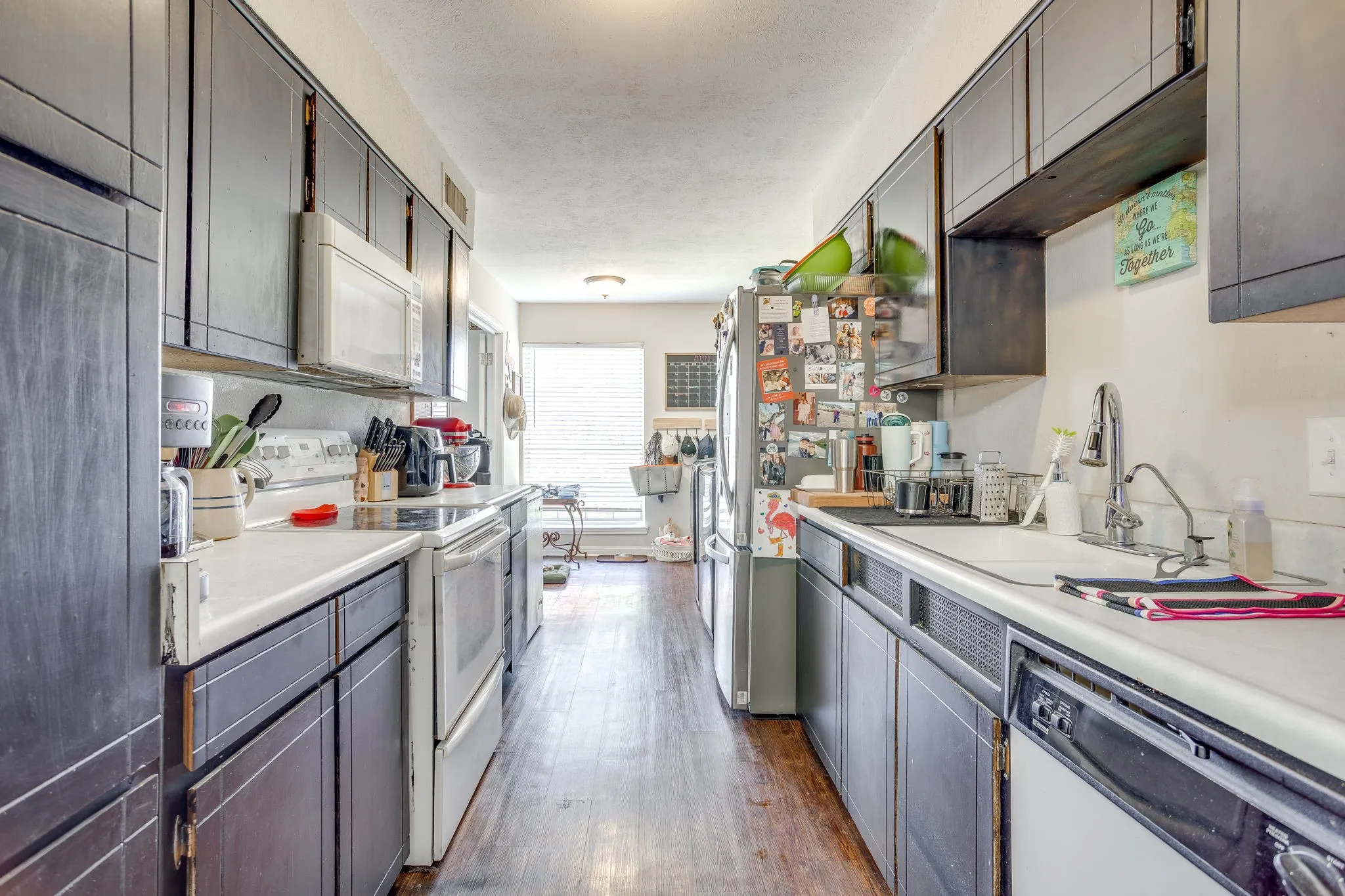 Galley kitchen featuring dark wood-finish cabinetry, white countertops, and wood-finish flooring