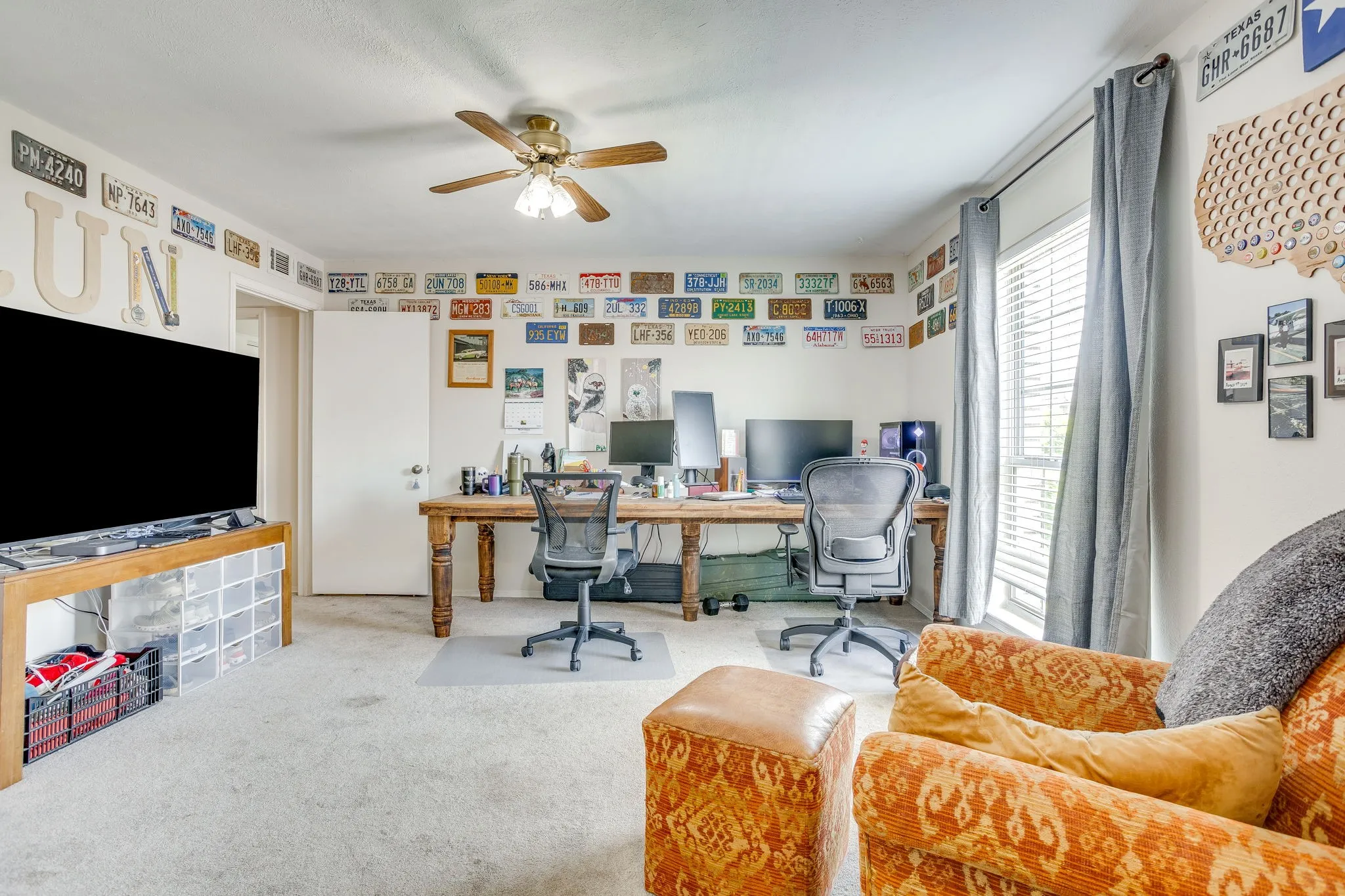 Versatile room featuring light-colored carpeting, a ceiling fan with integrated lighting, and a large window with blinds