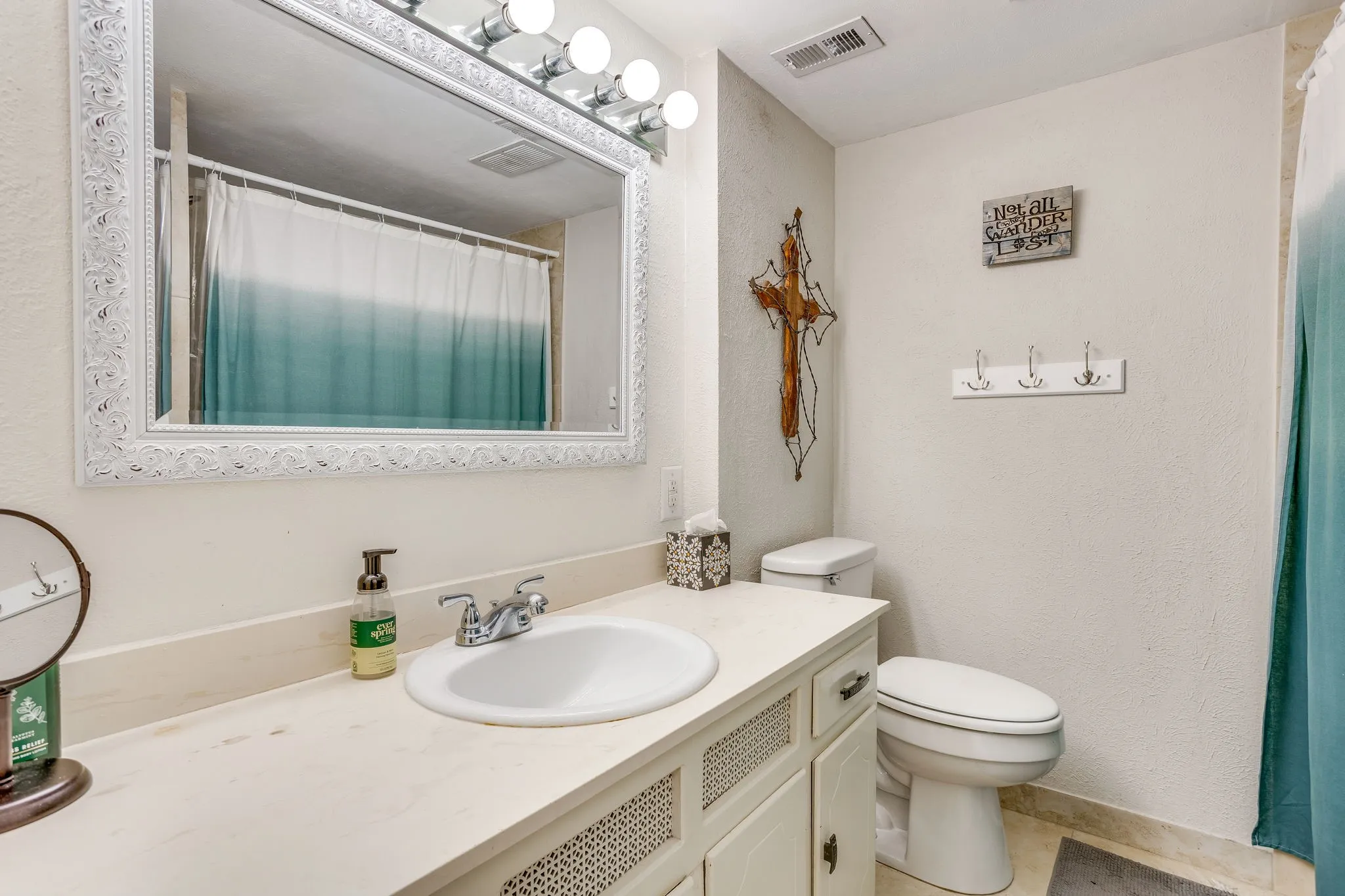 Bathroom vanity with a single basin sink, chrome faucet, and a large framed mirror with overhead vanity lighting