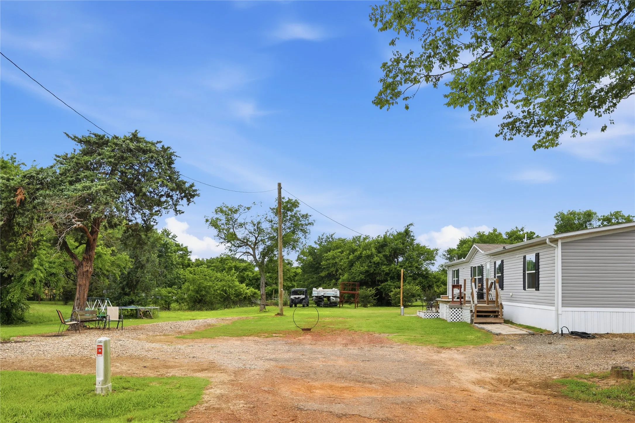 Expansive lot featuring a gravel drive and surrounding green spaces