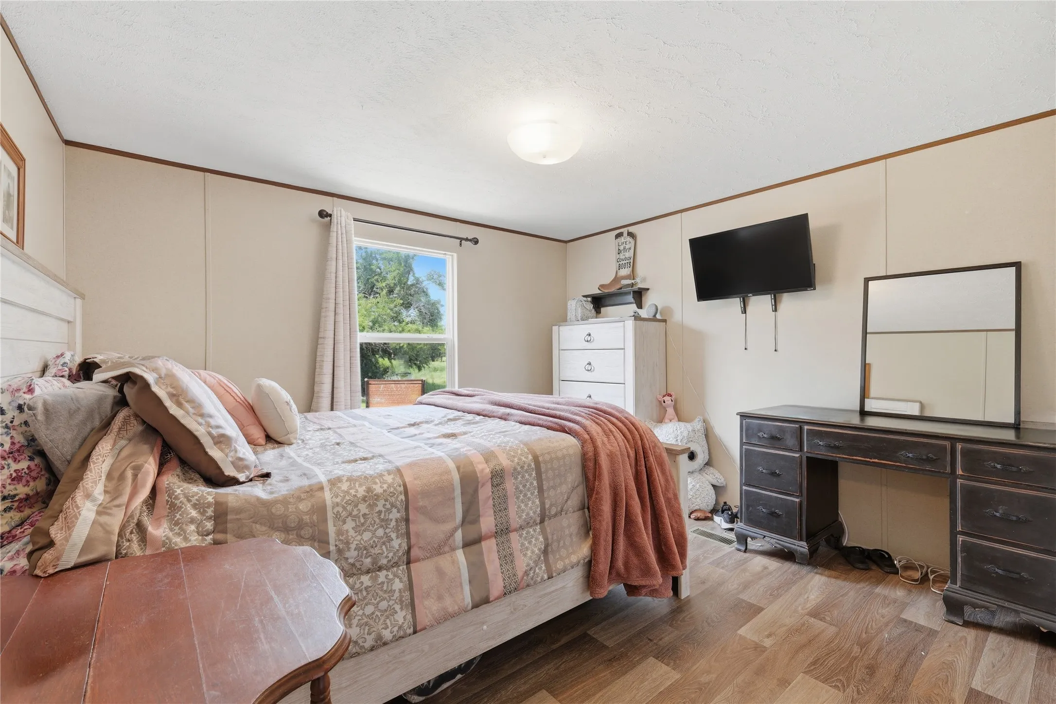 Bedroom featuring wood-finish flooring, a white paneled headboard, and light-colored wall paneling