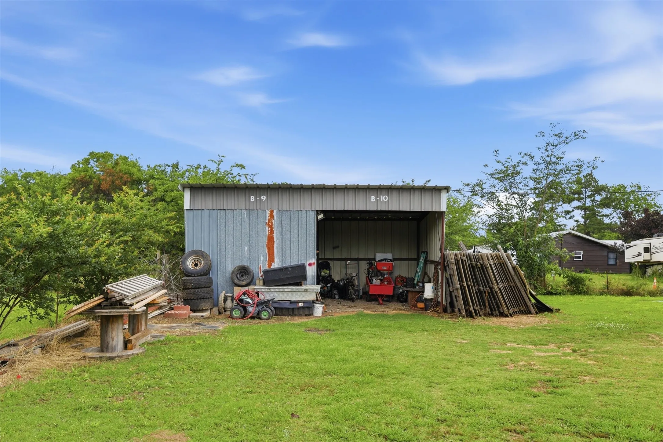 Metal-sided utility structure with an open bay and a corrugated metal roof