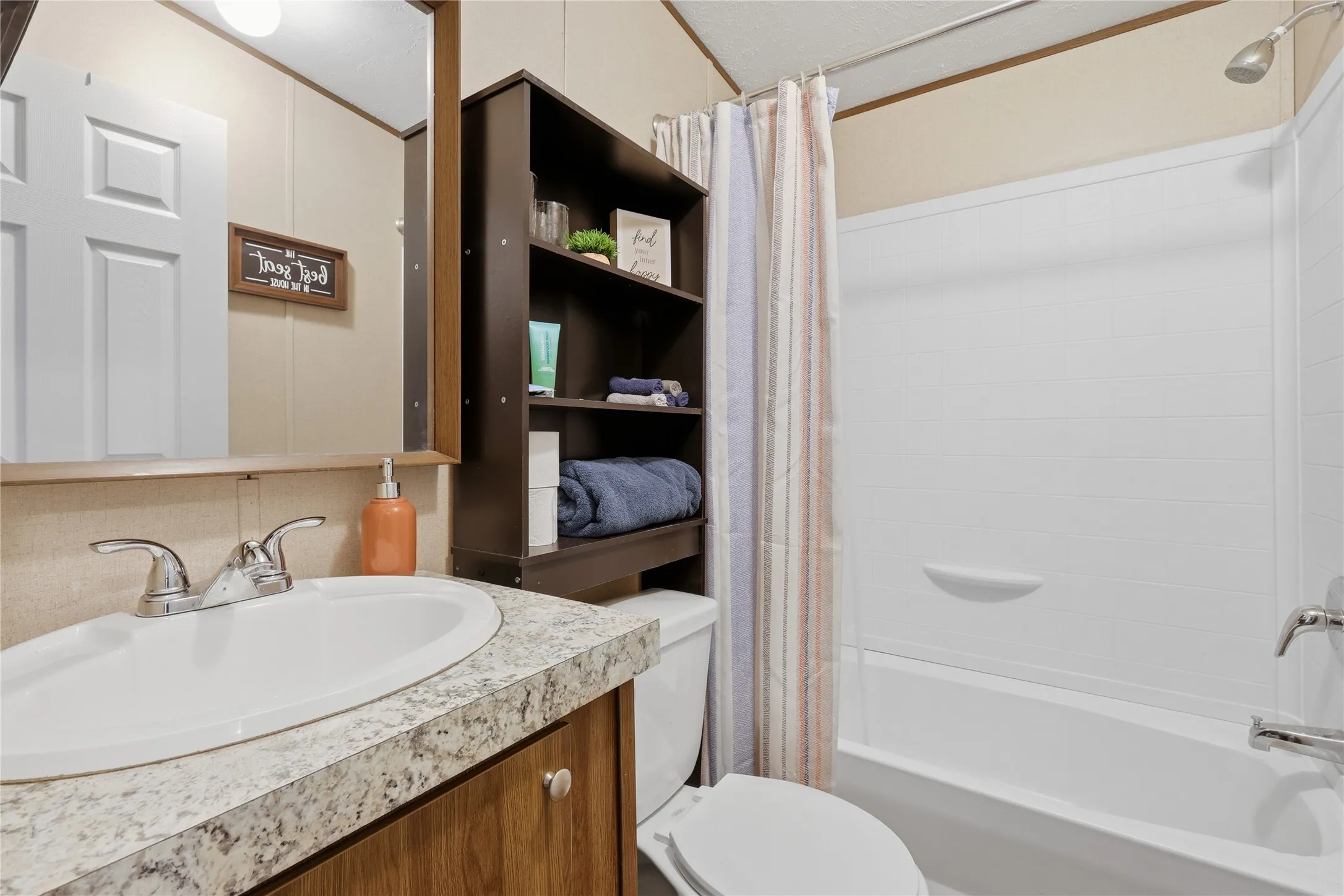 Bathroom vanity featuring a white oval sink, chrome faucet, and a stone-look countertop