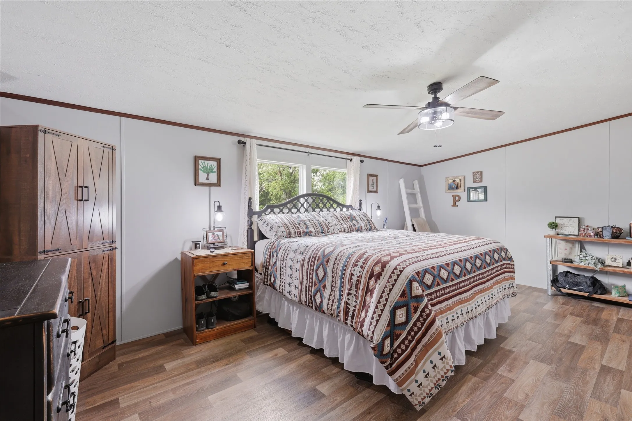 Spacious room featuring wood-finish flooring, a ceiling fan with integrated lighting, and a large window providing natural light